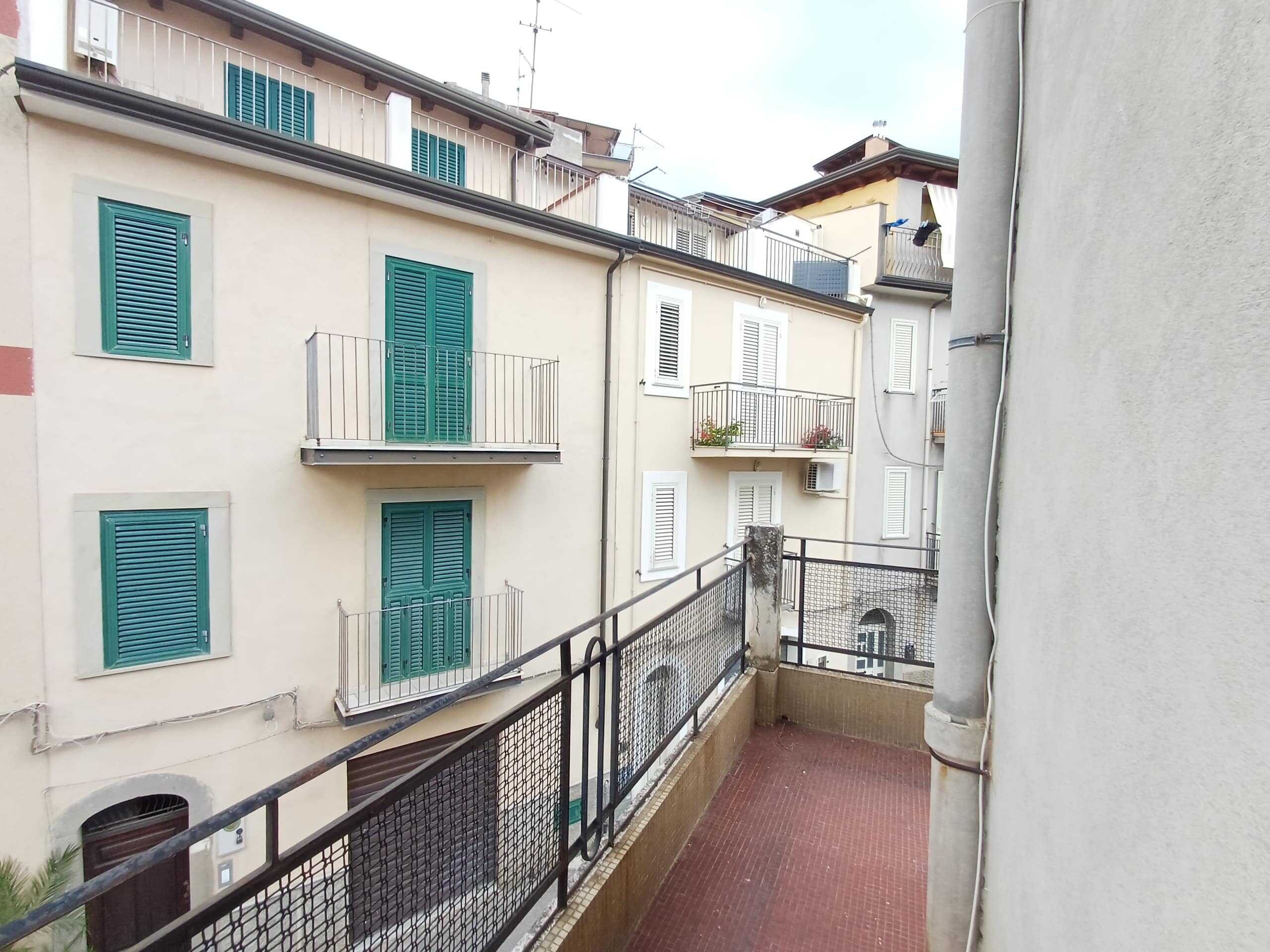 Balconi di case con persiane blu e balconi in ferro, vista su cortile condominiale, edifici storici e dettagli architettonici, ambientazione urbana italiana.