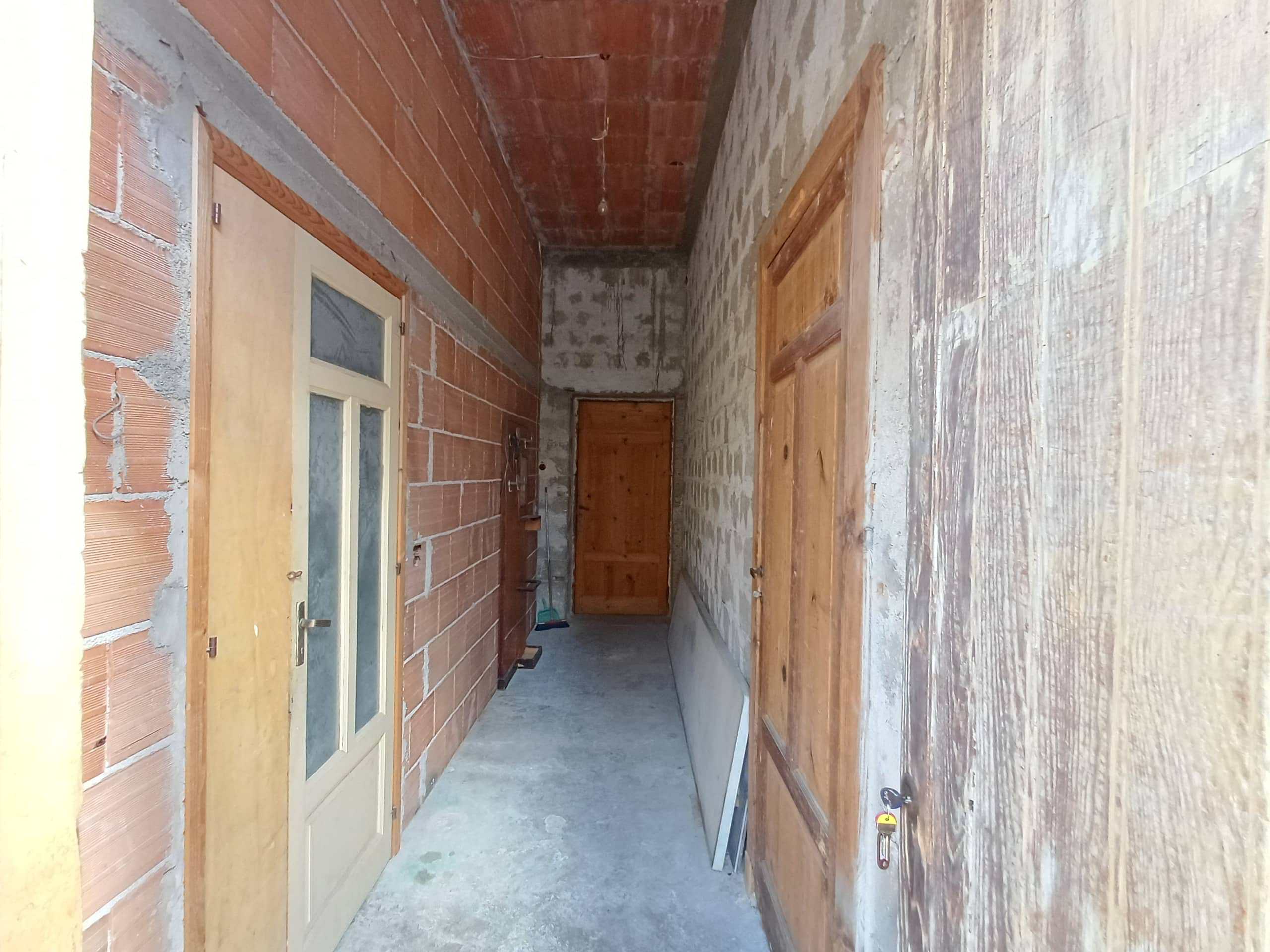 Ripresa di un corridoio in costruzione, con pareti in mattoni e pannelli in legno, pronto per essere rifinito e completato, ideale per chi cerca servizi di ristrutturazione edilizia.