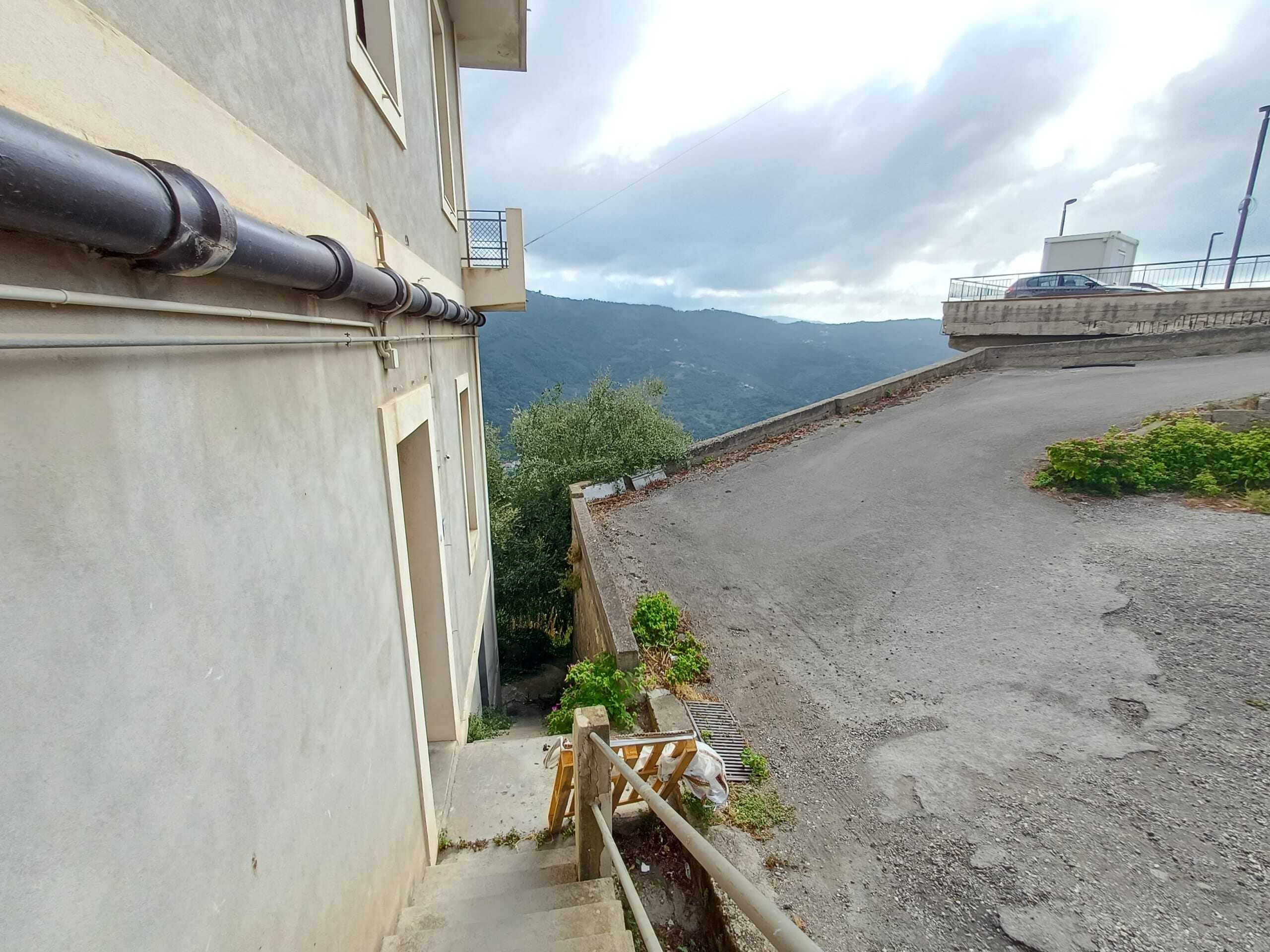 Veranda di una casa in collina con vista sui monti e strada in pendenza, atmosfera di tranquillità e natura circostante, ideale per eventi all'aperto e relax con viste panoramiche in Italia.