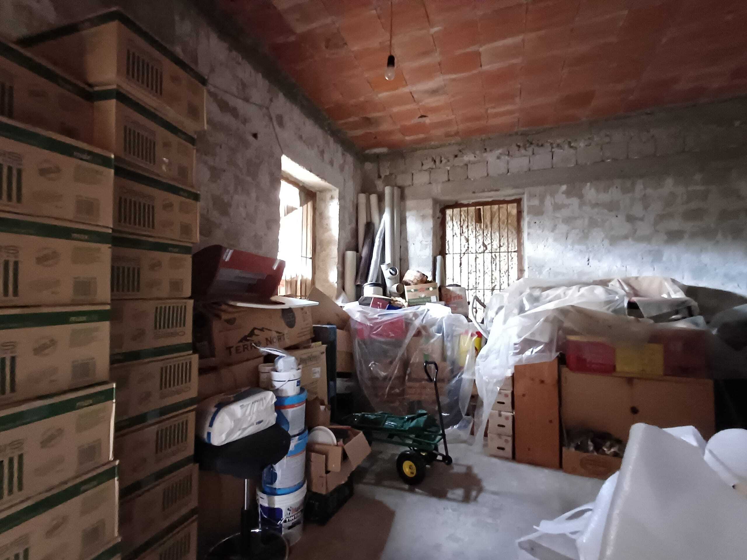 Scaffali pieni di scatole, materiali edili e attrezzi in un magazzino in corso di ristrutturazione o riorganizzazione.