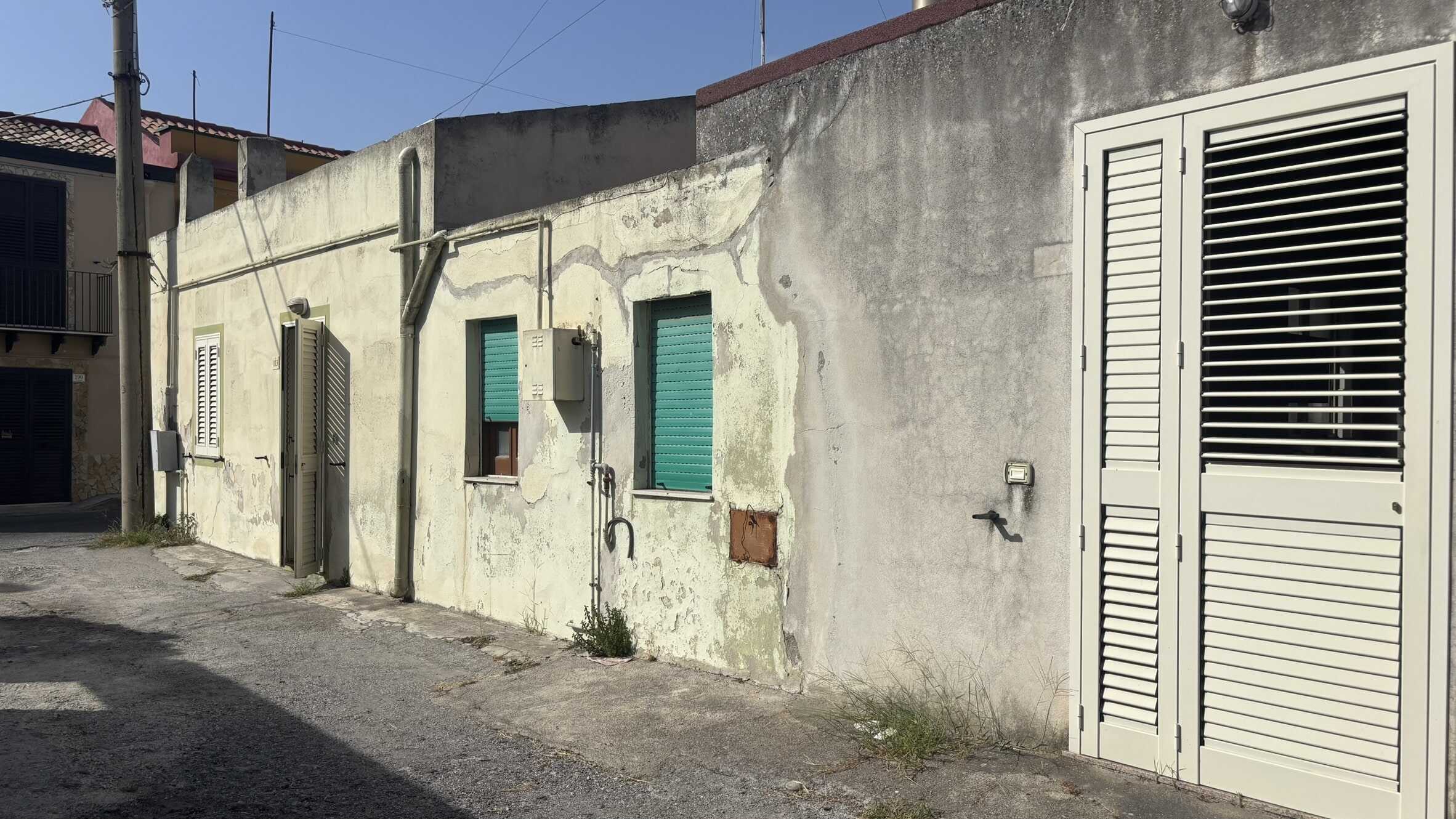 Vecchio edificio residenziale con pareti in pietra e serramenti in alluminio, esempio di ristrutturazione abitativa in stile urbano. Edificio con infissi in pvc e pannelli oscuranti, situato in zona residenziale a NextCasa.