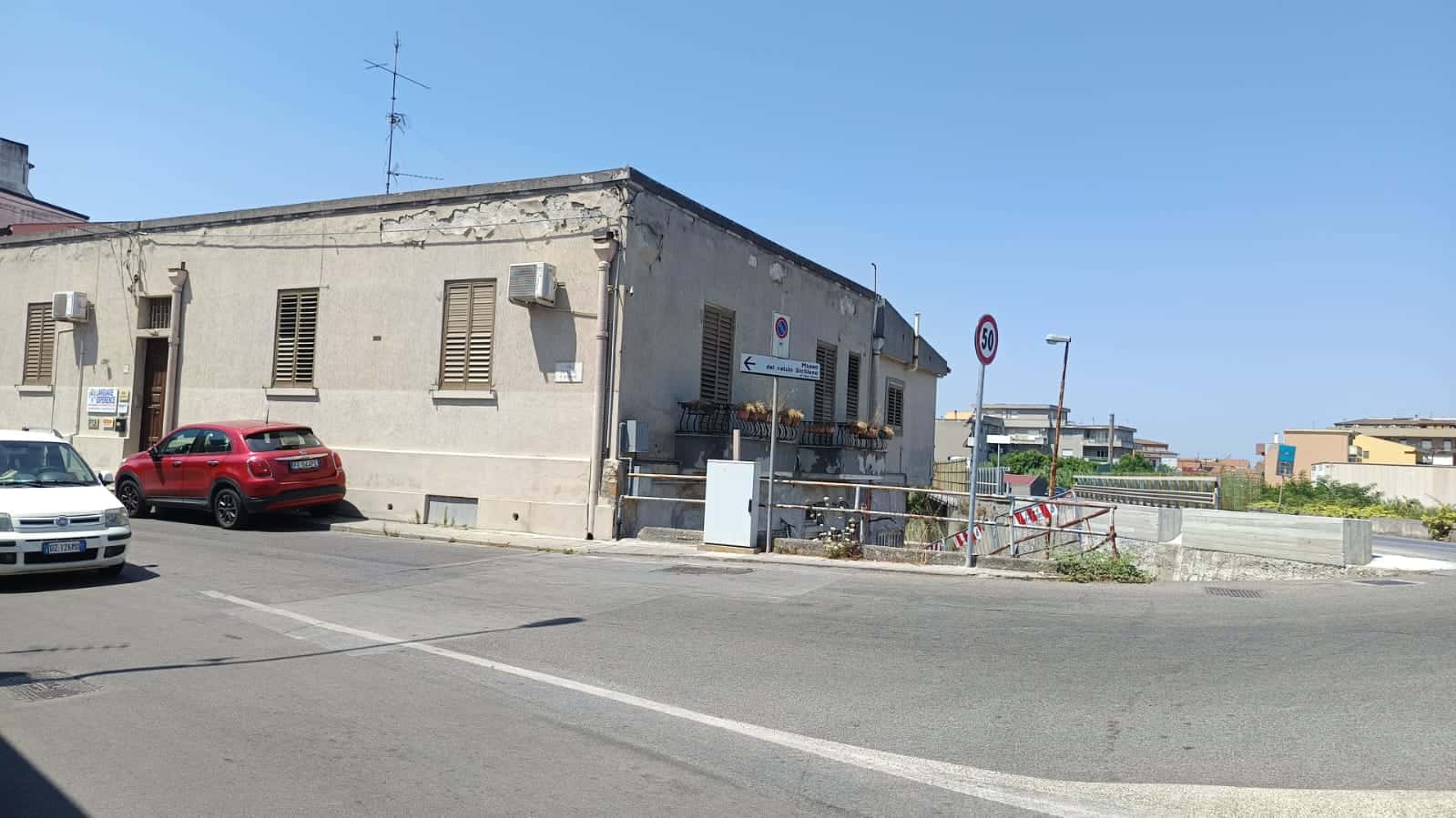 Edificio residenziale su strada urbana con veicoli parcheggiati e segnaletica stradale, esempio di investimento immobiliare e mercato immobiliare, con un aspetto autentico e urbano.