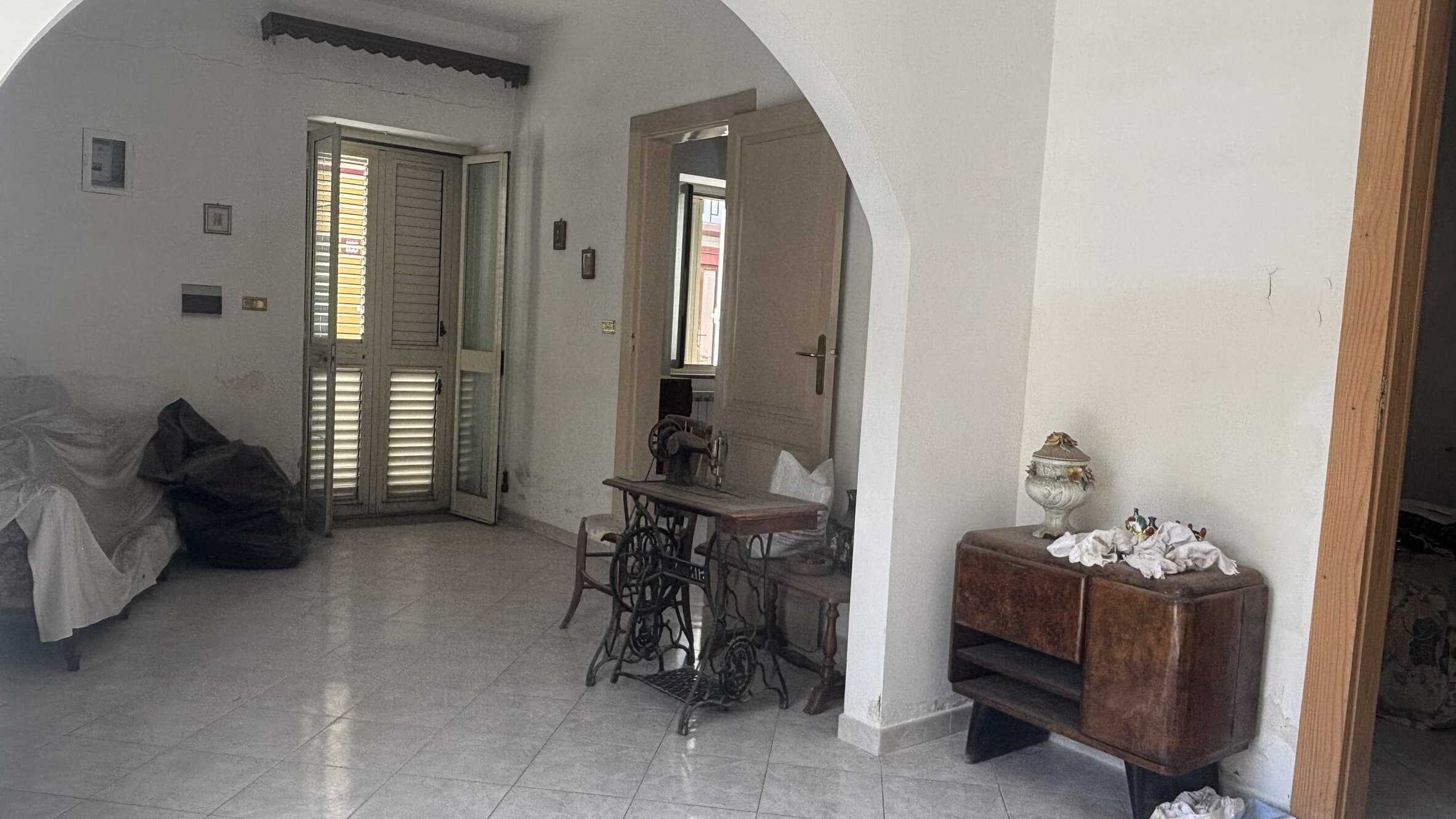 Vecchio ambiente domestico con mobili vintage, porta a vetri, decorazioni classiche e oggetti d'epoca, ideale per chi cerca soluzioni di interni con charme storico.