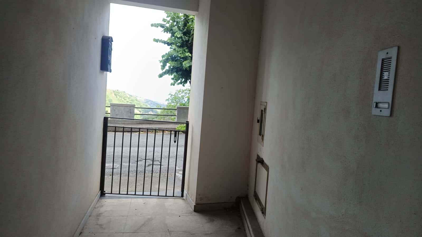Balcone di un appartamento con vista su un paesaggio verde e collinare, accessibile tramite porta di uscita con ringhiera in ferro, ideale per ambienti residenziali e immobili in vendita o affitto.