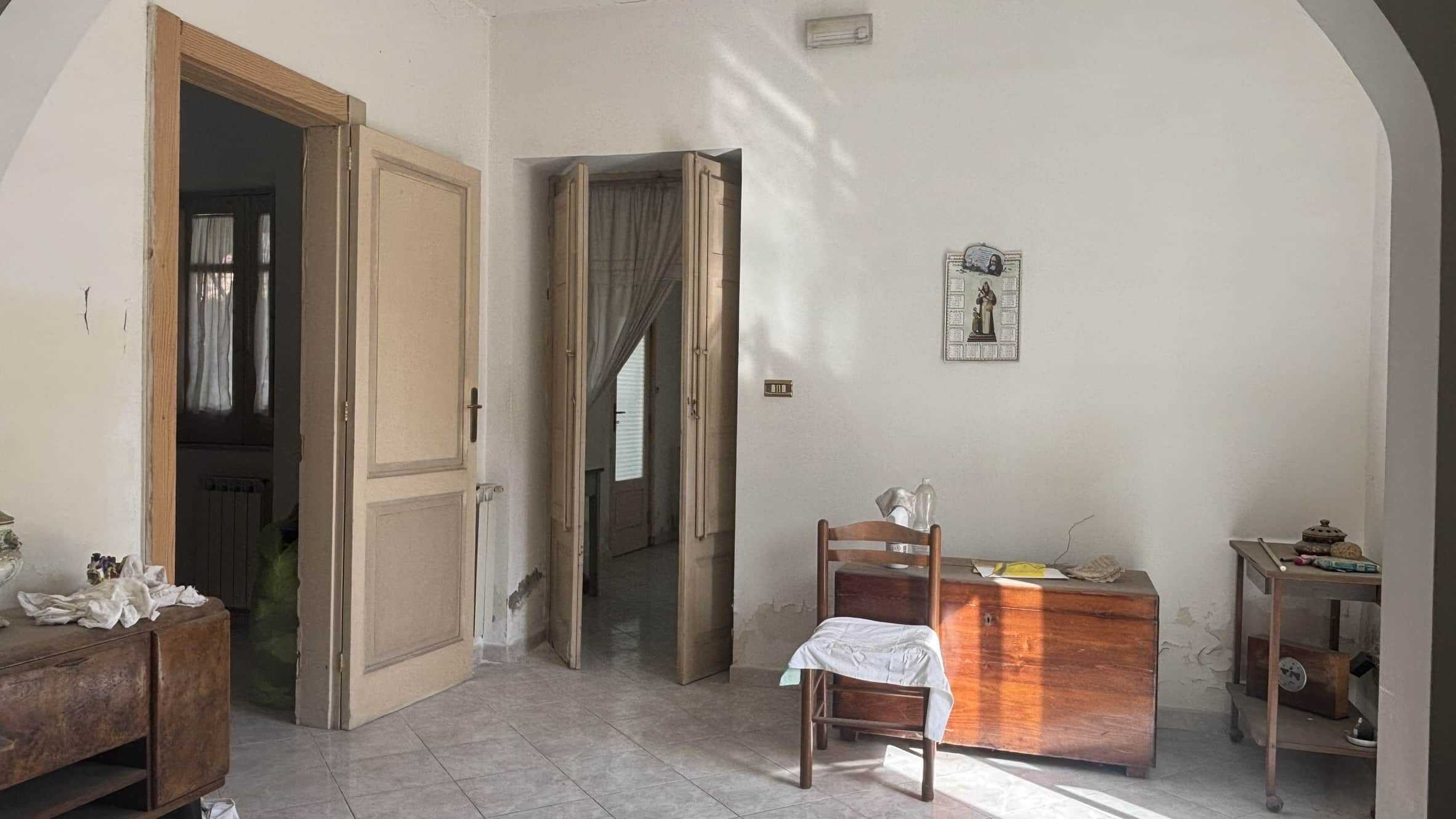 Vecchia casa con arredi tradizionali e pareti in bianco, ambientazione rustica e autentica, ideale per mercato immobiliare e investimenti in Italia.
