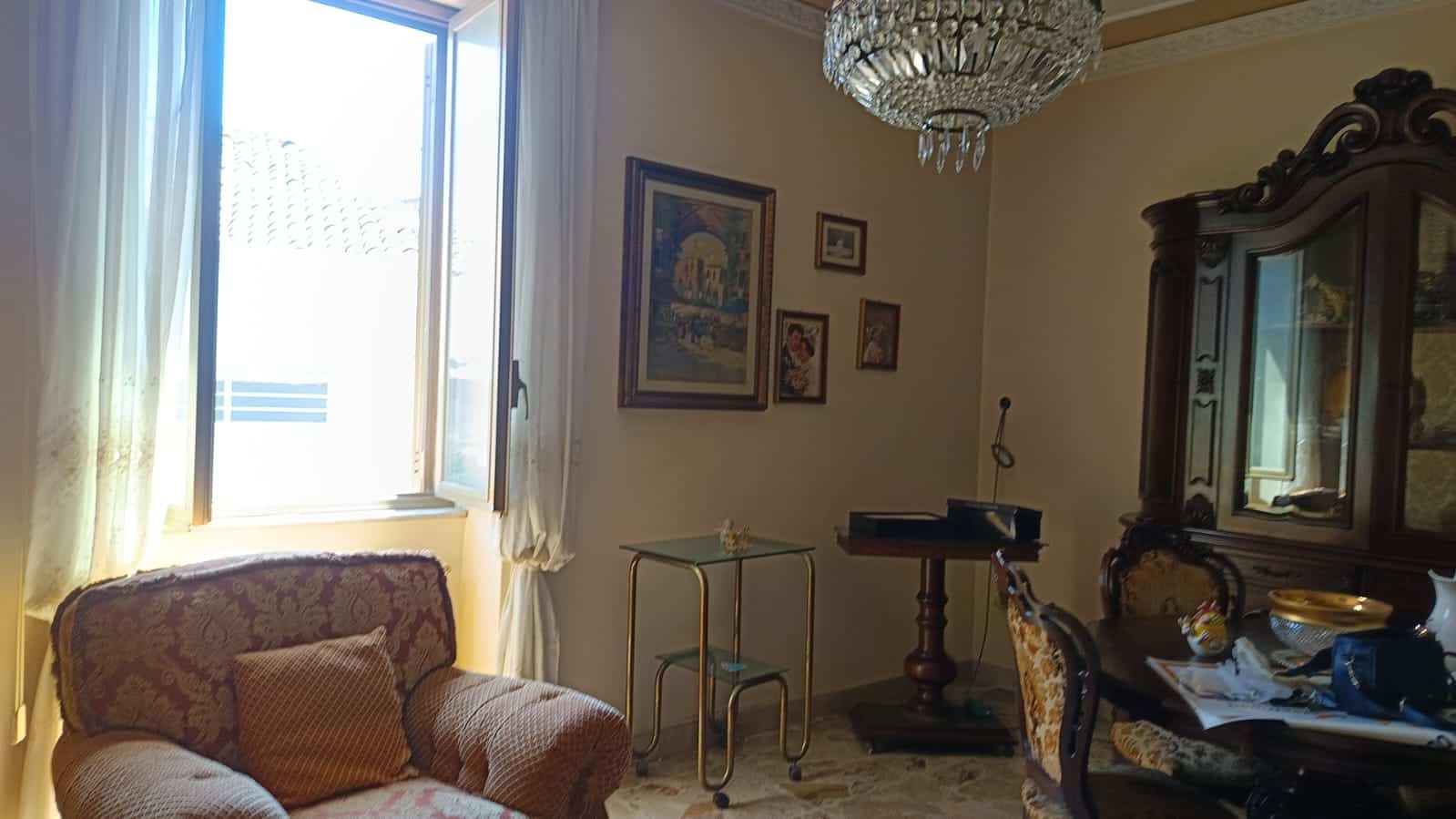 Finestra aperta in un soggiorno classico con arredi eleganti, illuminato dalla luce naturale e decorato con quadri alle pareti, creando un'atmosfera accogliente e luminos https://www.nextcasa.it.