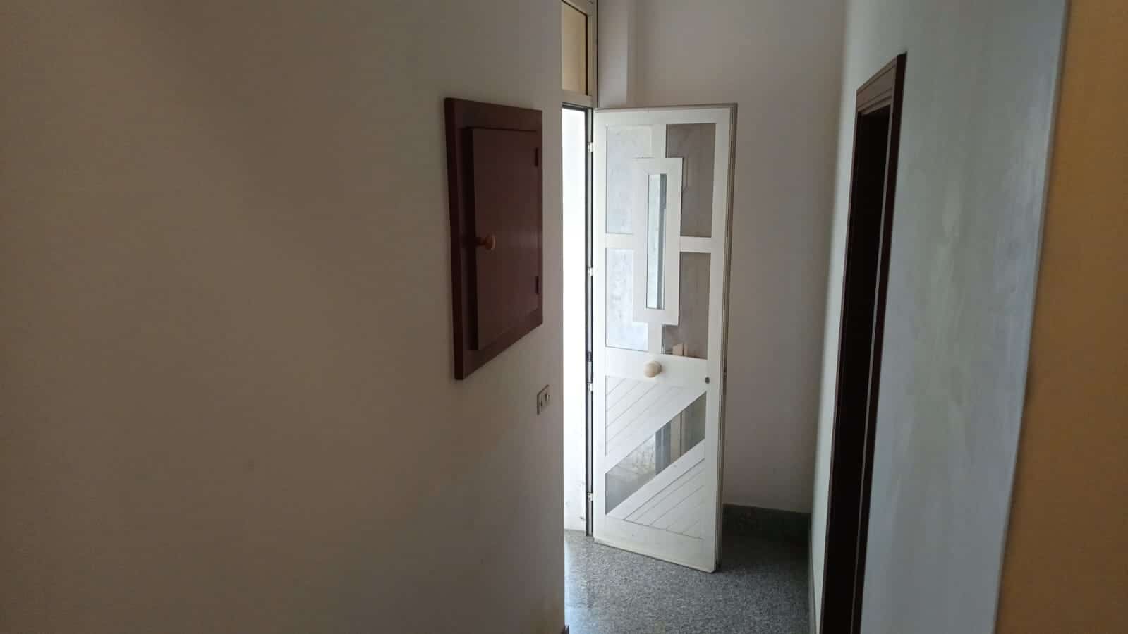 Porta blindata bianca con vetri, ingresso di un appartamento in stile minimalista, pareti chiare e pavimento in marmo, ambiente luminoso e accogliente.