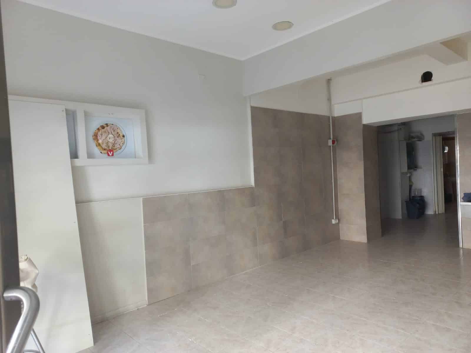 Open spazio commerciale ristrutturato con pareti rivestite in piastrelle beige, soffitto bianco, area luminosa e senza mobili, pronto per allestimento in ambito immobiliare o commerciale.
