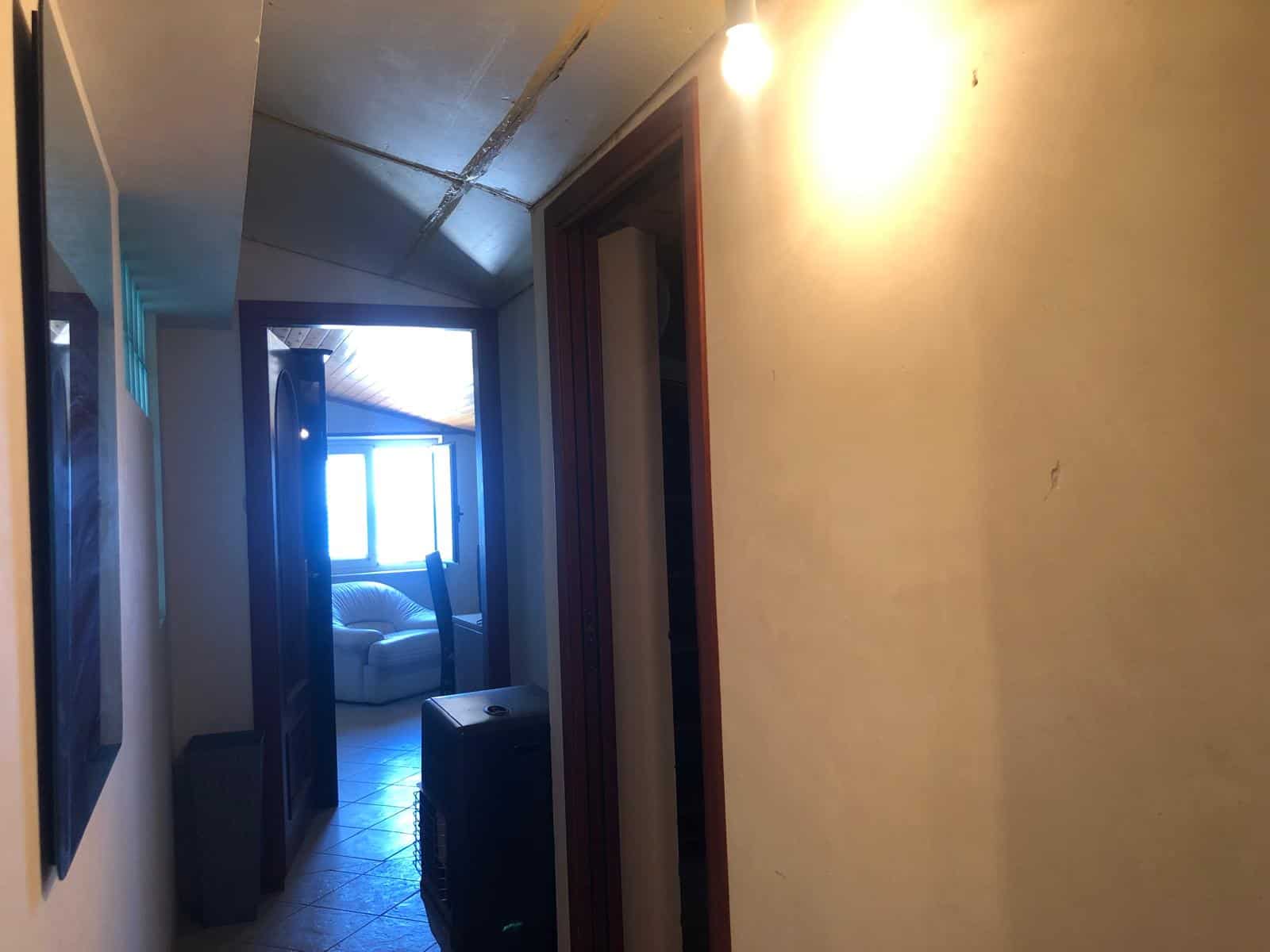 Finestra luminosa in soggiorno con divano, vista leggera, spazio accogliente, arredamento semplice, luce naturale, ambiente di casa, pareti chiare, atmosfera calda, stile tradizionale, comfort domestico.