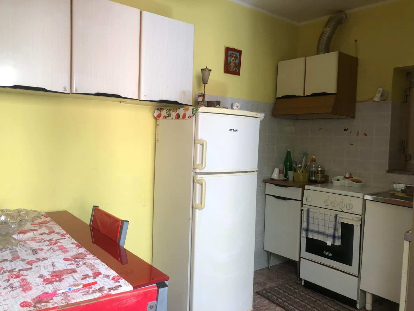 Elettrodomestici cucina vecchio stile con frigorifero, forno e mobili da cucina in ambiente domestico.