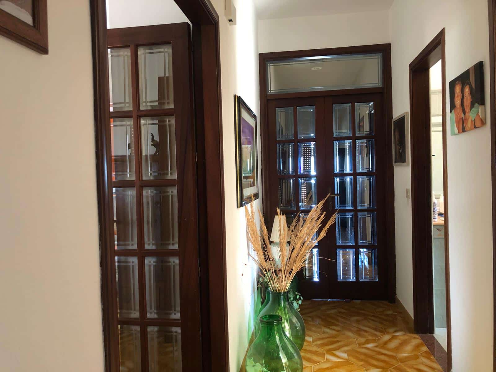 Vetro e legno porte interne, ingresso di casa con vasi decorativi, ambiente luminoso e accogliente, pavimento in maiolica, stile classico e caldo, arredamento tradizionale e dettagli di arte domestica.