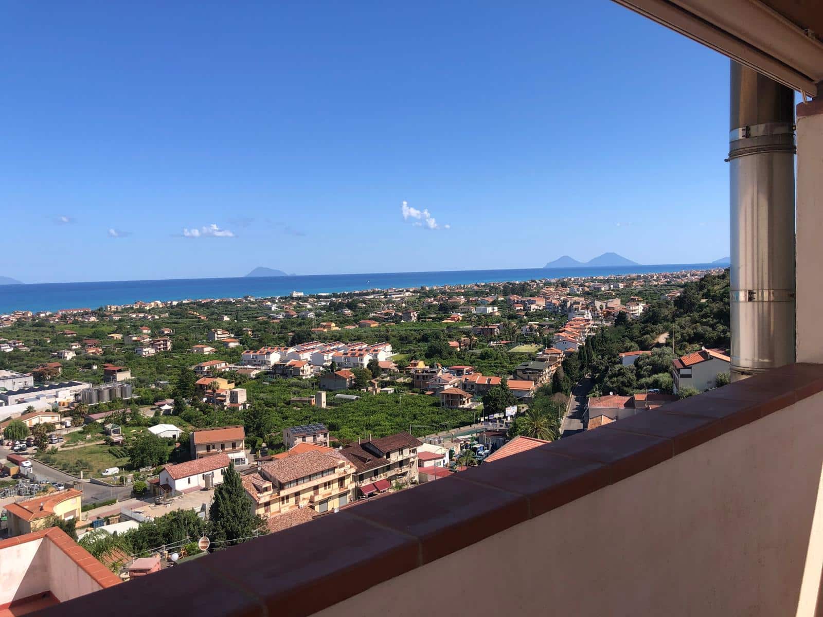 Vista panoramica mare e città dalla terrazza di un appartamento vicino al mare in Calabria. Panorama mozzafiato con mare cristallino, colline e isole sullo sfondo, ideale per immagini di immobili sul lungomare.