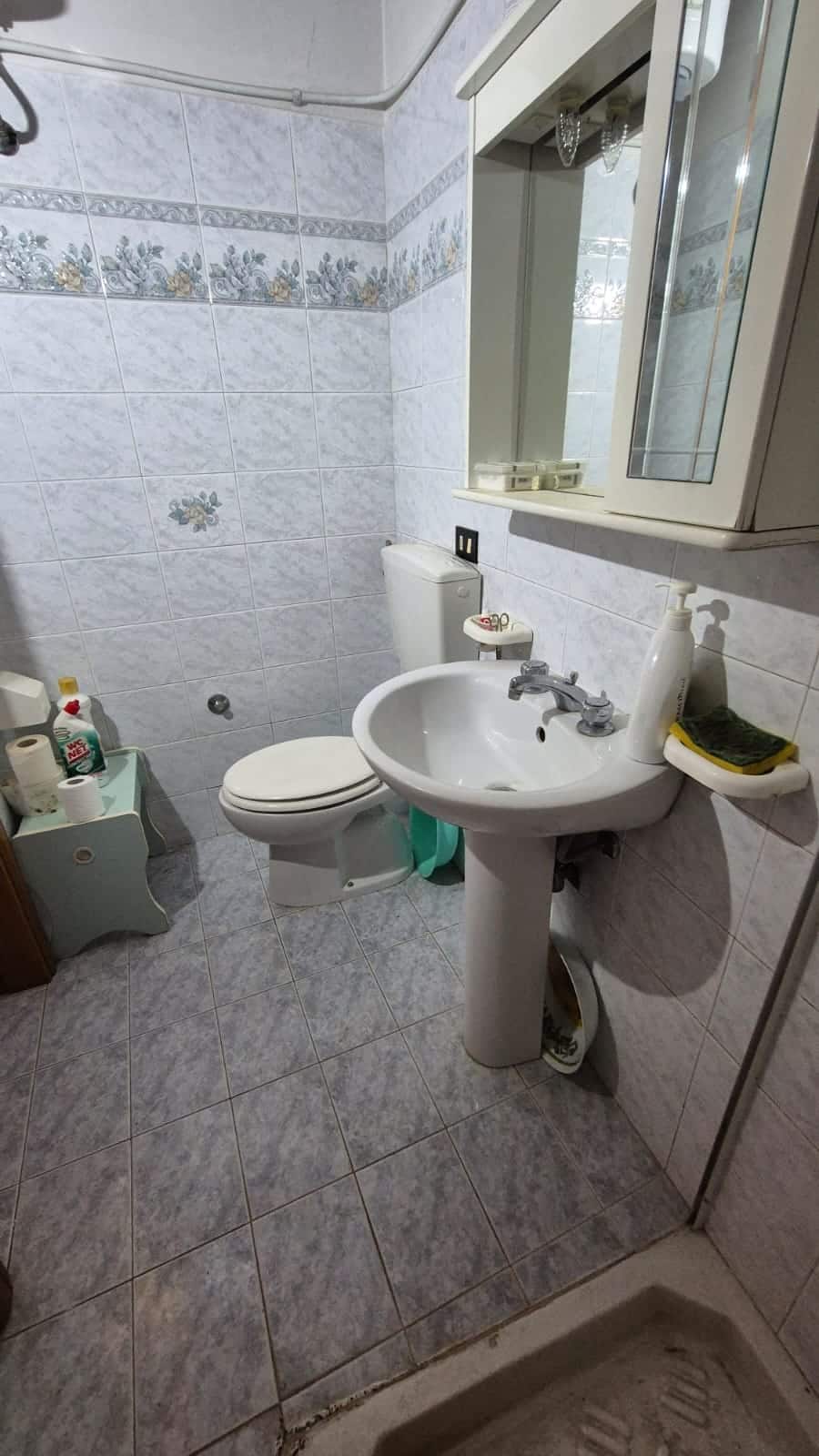 Lavabo e toilette in un bagno di piccole dimensioni, pareti rivestite con piastrelle decorative e mobili da bagno funzionali, ideale per ottimizzare gli spazi.