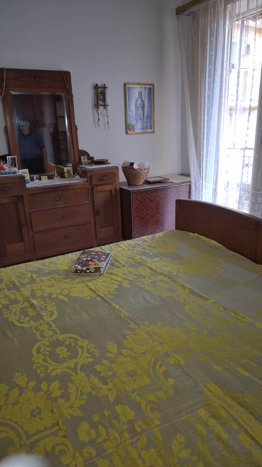 Letto matrimoniale con copriletto giallo decorato, arredamento in stile classico.