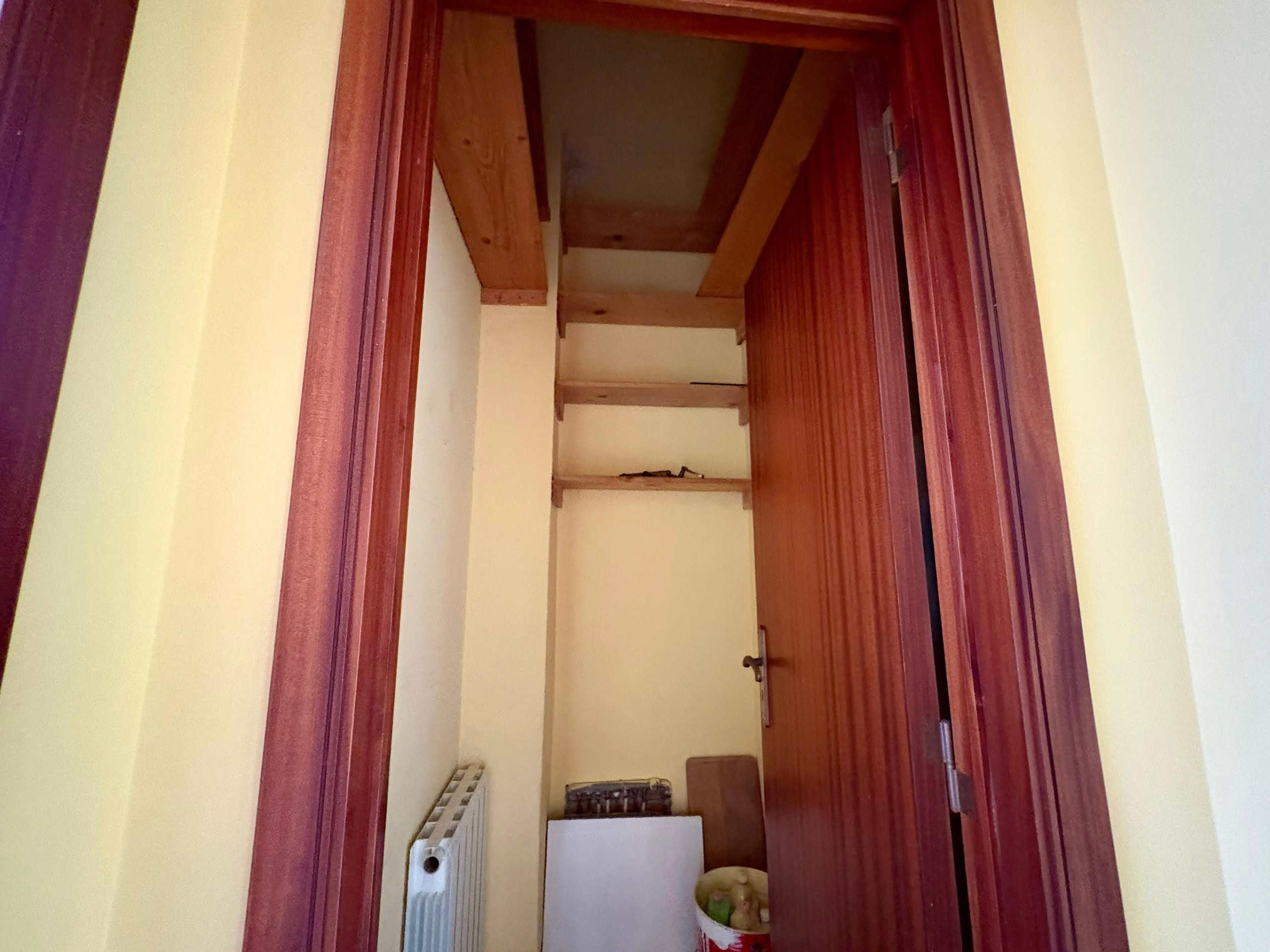 Spiacevole ripostiglio in legno con scaffali, porta scorrevole, radiatore e scatola di conservazione, perfetto per spazio di archiviazione in case o appartamenti, esempio di organizzazione funzionale e ottimizzazione degli ambienti.