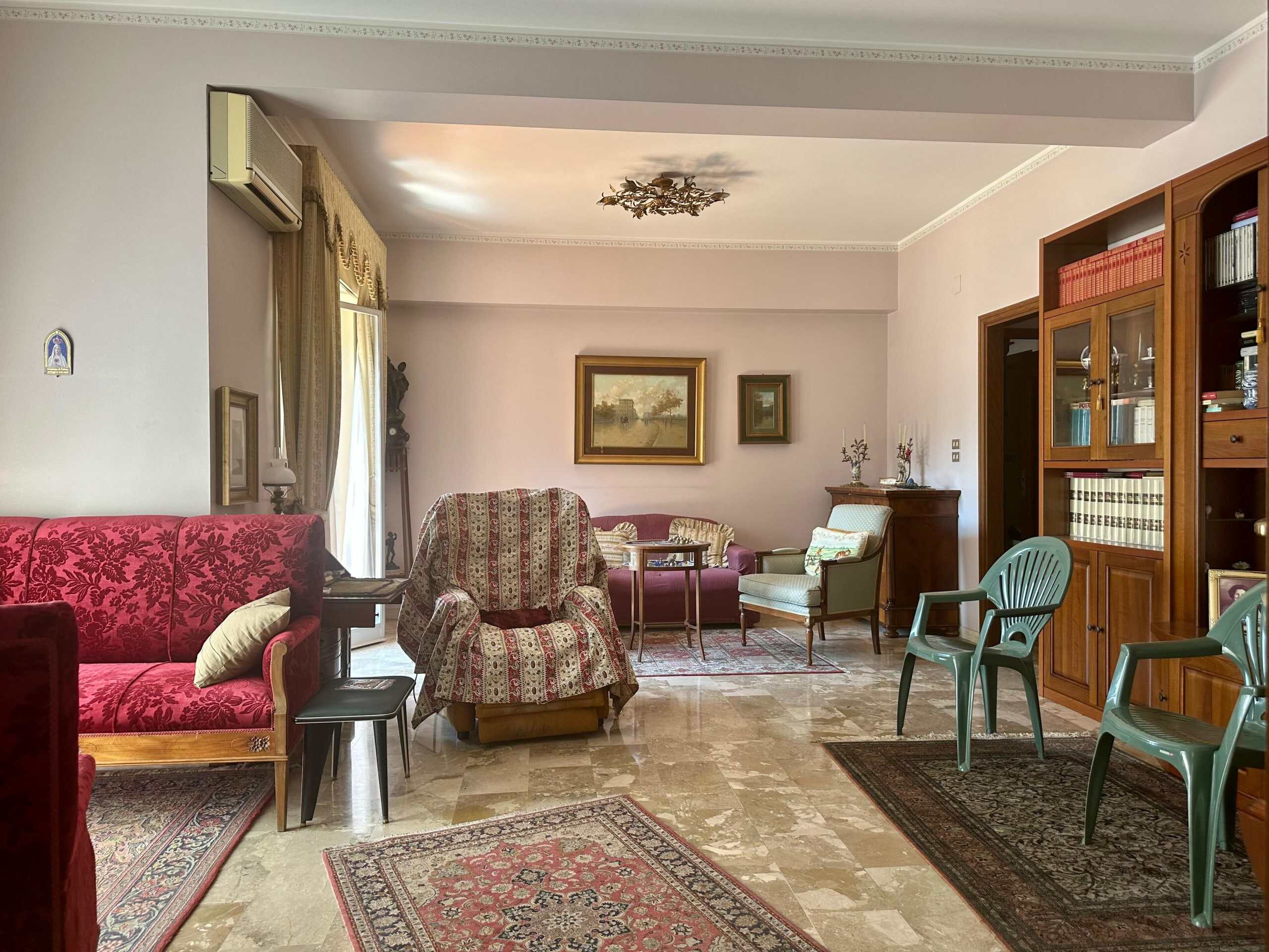 Elegante soggiorno in stile Classico con arredi in legno, divani e poltrone rivestiti in stoffa, tappeti persiani, librerie in legno e dettagli decorativi. Perfetto per un ambiente accogliente e raffinato.