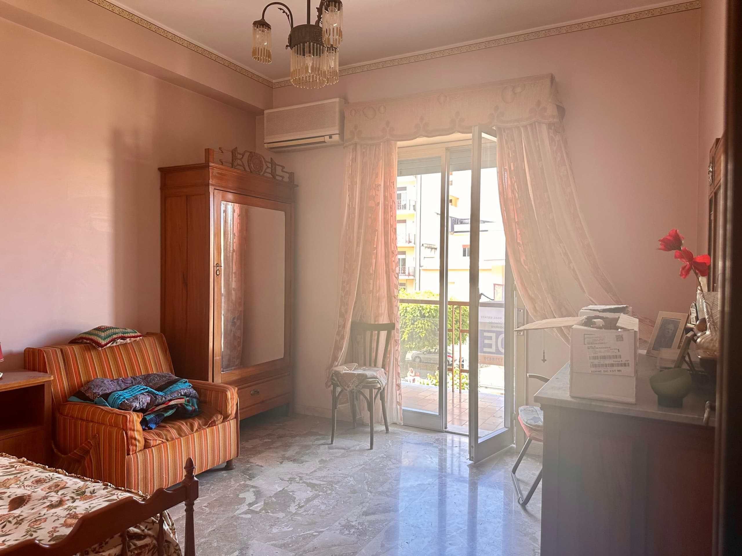 Armadio in legno con specchio e soggiorno con divano a righe arancioni, balcone con tende leggere, dettagli di arredamento classico, soluzione abitativa elegante e luminosa.