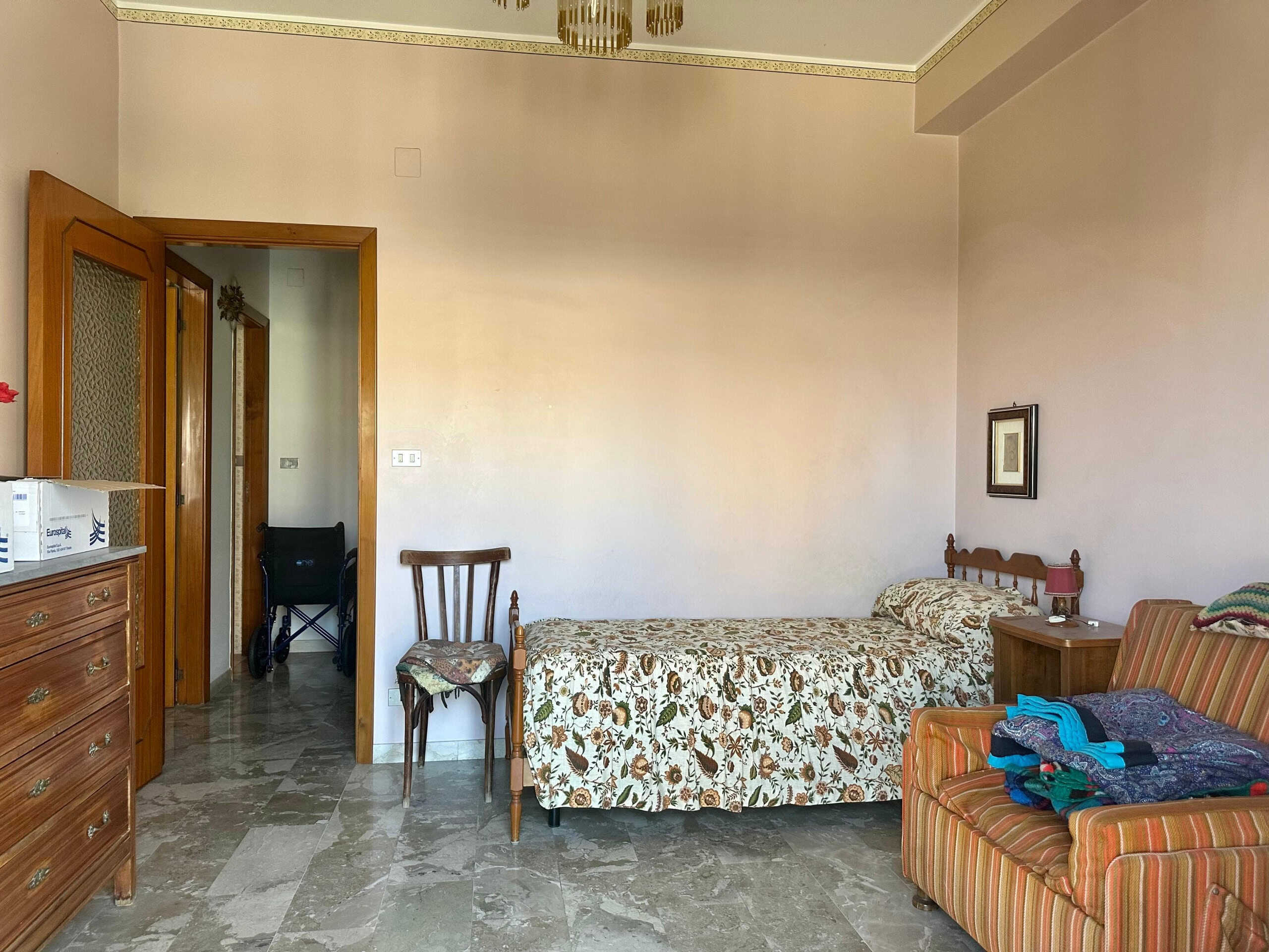 Camera doppia in stile classico con letto singolo, armadio, poltrona con rivestimento a righe e mobile in legno, ambiente residenziale per affitto o vendita - NextCasa.