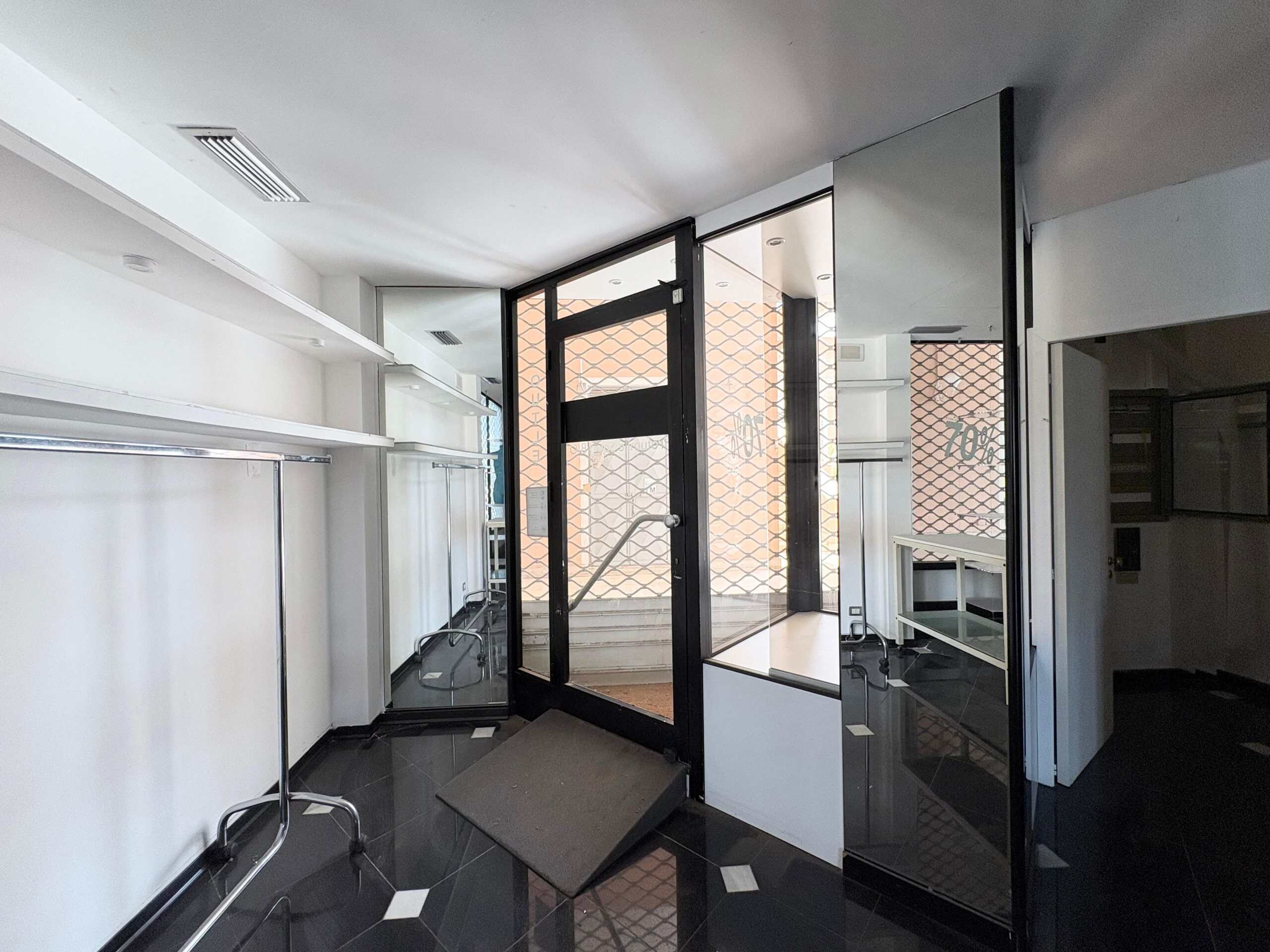 Negozio in affitto a Milano con ingresso elegante e vetrate protette, interni moderni con dettagli di design e pavimento lucido, eventuale spazio commerciale o ufficio.