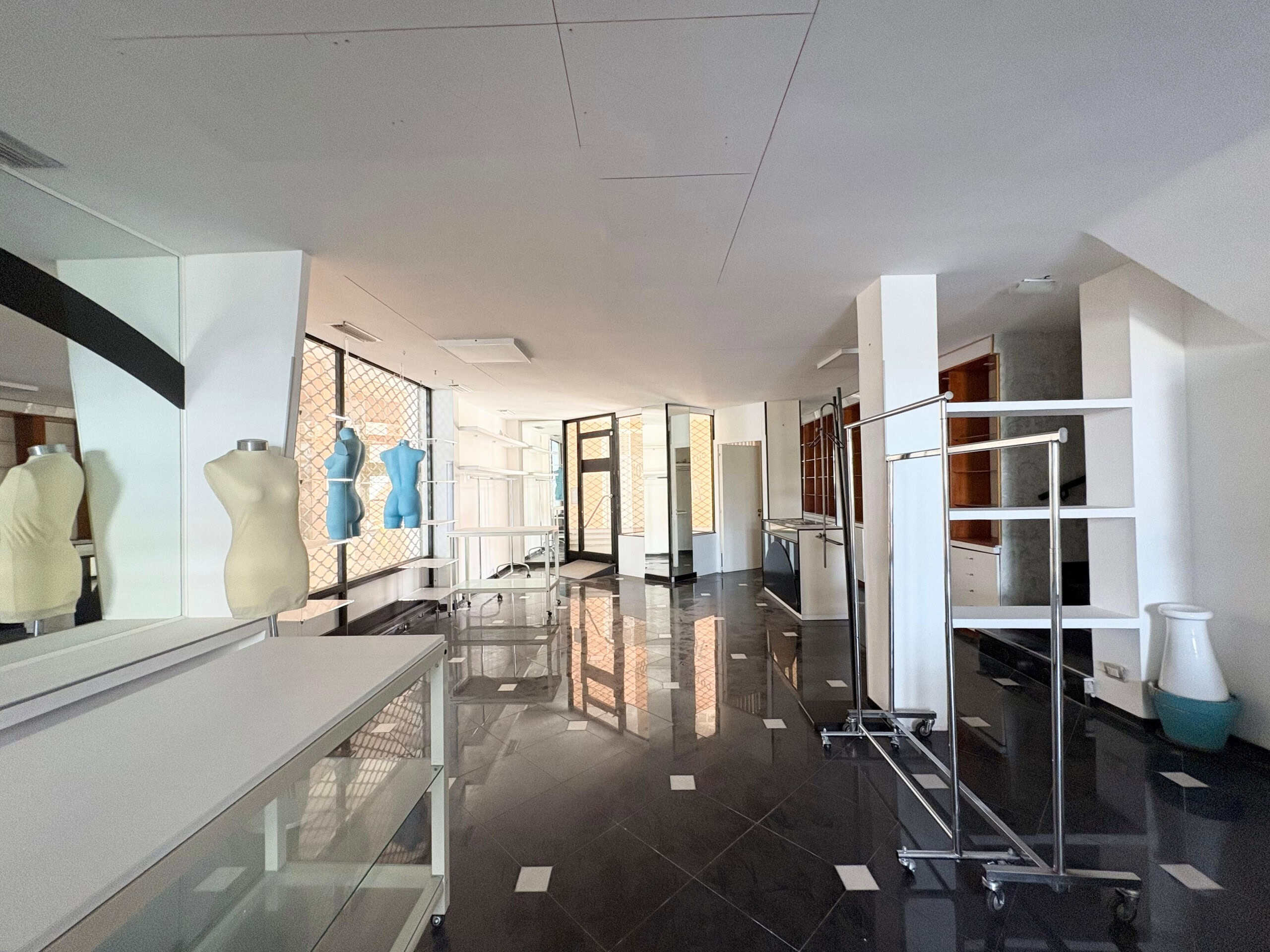 Manichini per negozio di moda in vendita su spazio commerciale vuoto con scaffali e rack in metallo, negozio di abbigliamento vuoto, spazio commerciale per negozio di abbigliamento, arredamento di negozio di moda, allestimento negozio di abbigliamento, luci naturali, grande vetrina, interni moderni, pavimento in piastrelle nere e bianche, spazio commerciale pronto per apertura, NextCasa, negozio di moda vuoto, fronte strada, spazio commerciale in affitto o vendita.