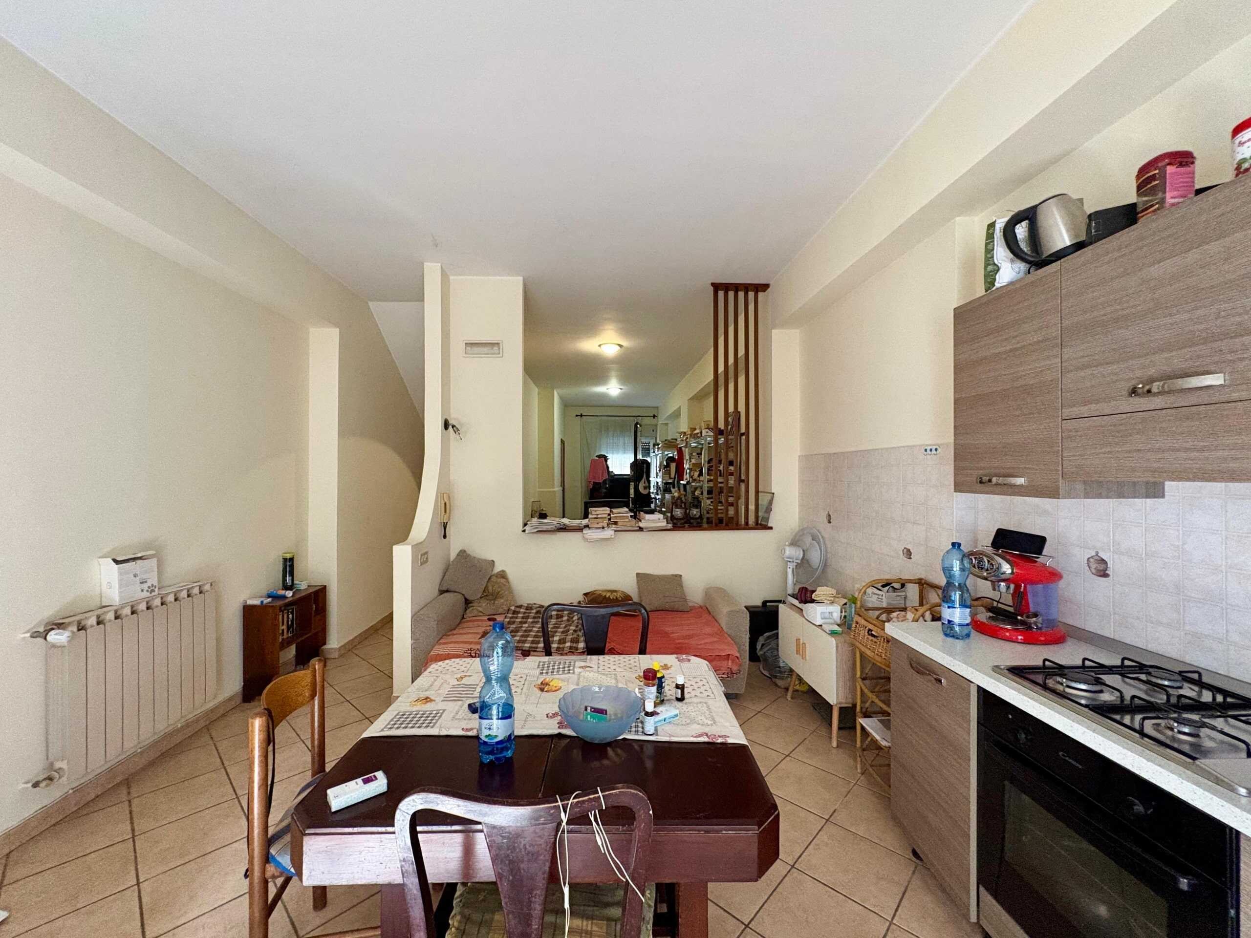 Angolo di cucina e zona living in appartamento con arredi pratici e abitabili, ideale per vivere in comodità; presenza di forno, cucina a gas e dettagli di arredamento quotidiano.
