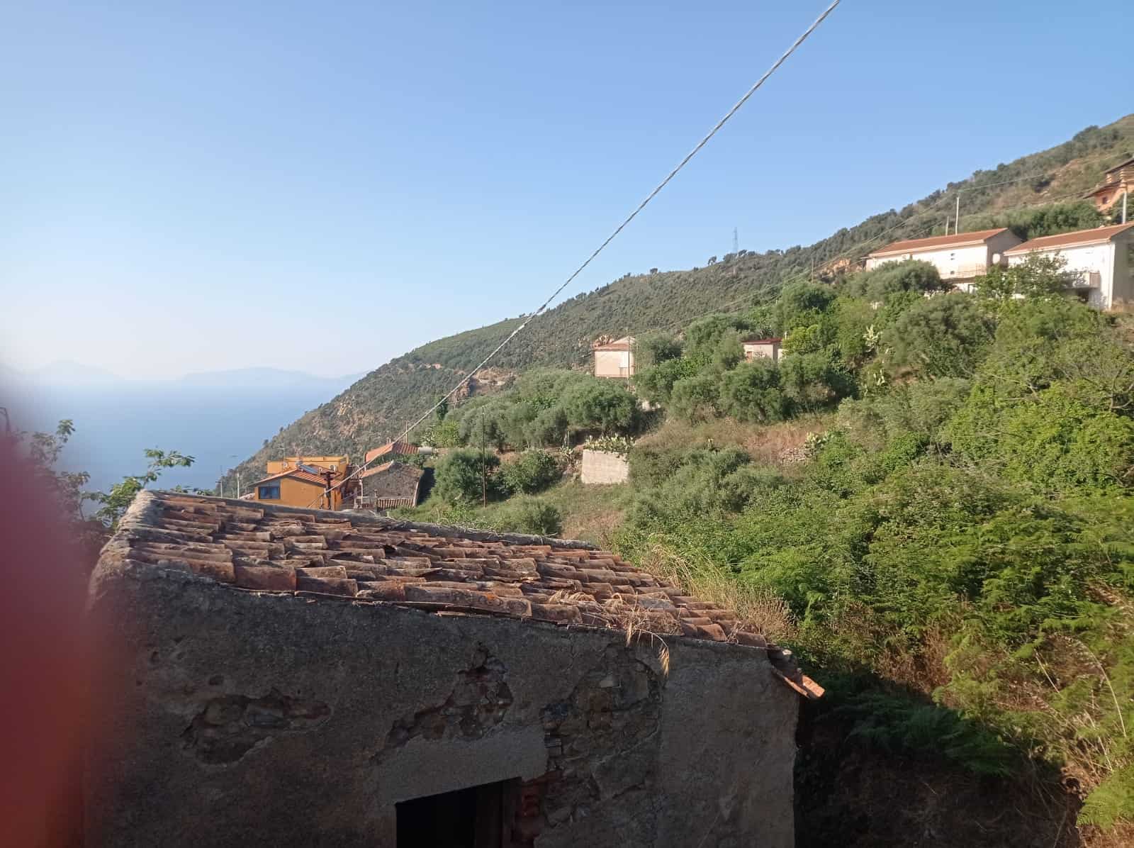Vecchio tetto in pietra e vista panoramica sulle case e colline verdi dei paesaggi rurali italiani.