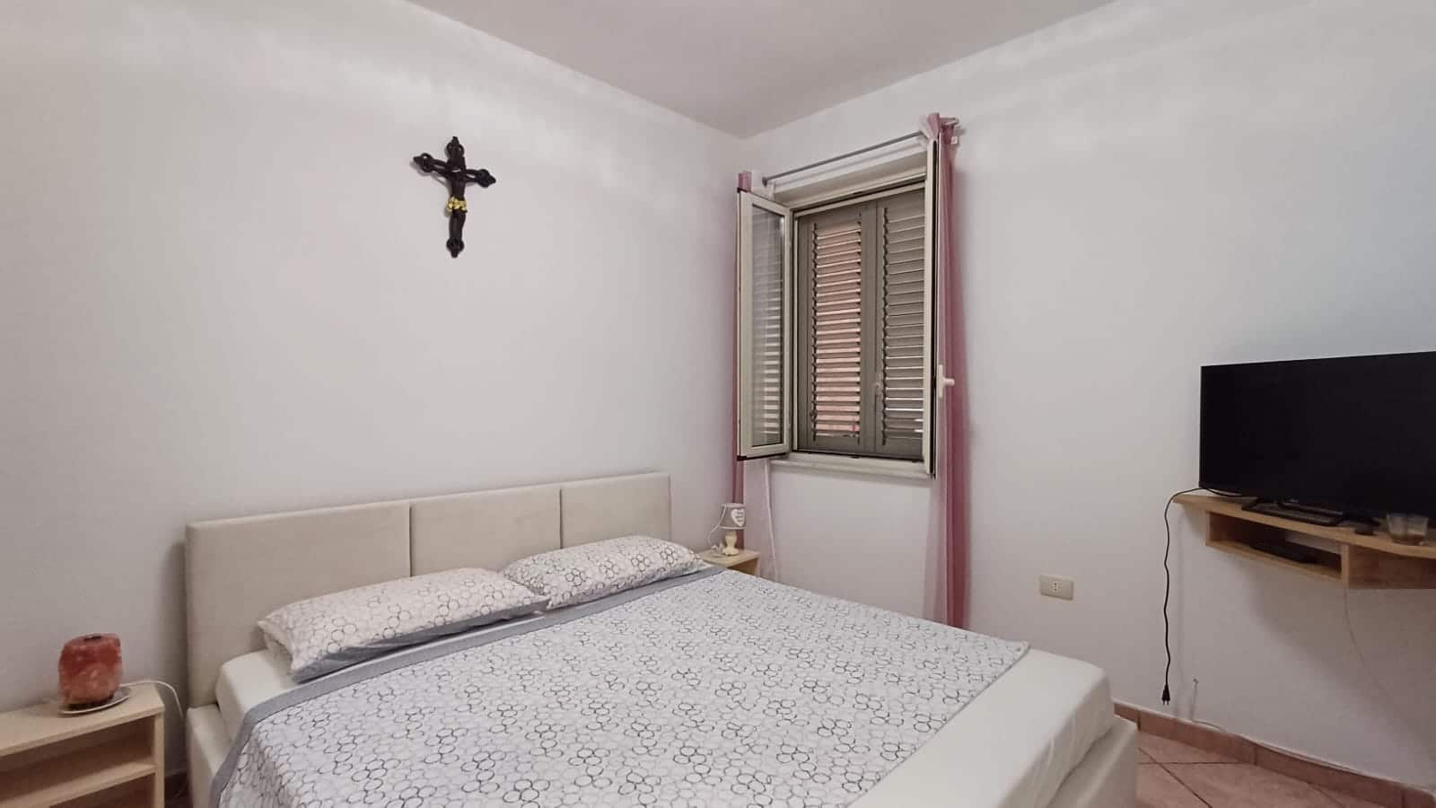 Lettera, immagini, cronologiaAlternative, camera da letto con finestra, TV e decorazioni semplici, esempio di arredamento casa, NextCasa, comfort abitativo.
