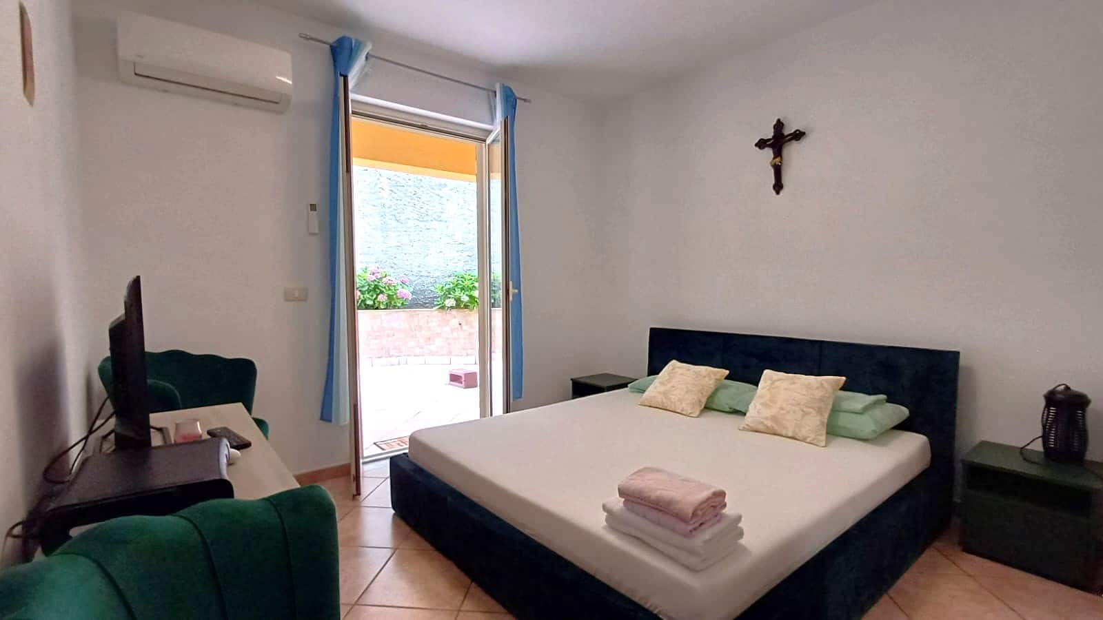Camera matrimoniale con accesso a terrazza, camera da letto con letto king size, stanza matrimoniale calda e accogliente, ambientazione di casa vacanza NextCasa, affaccio su balcone con fiori colorati, angolo relax con mobili eleganti.