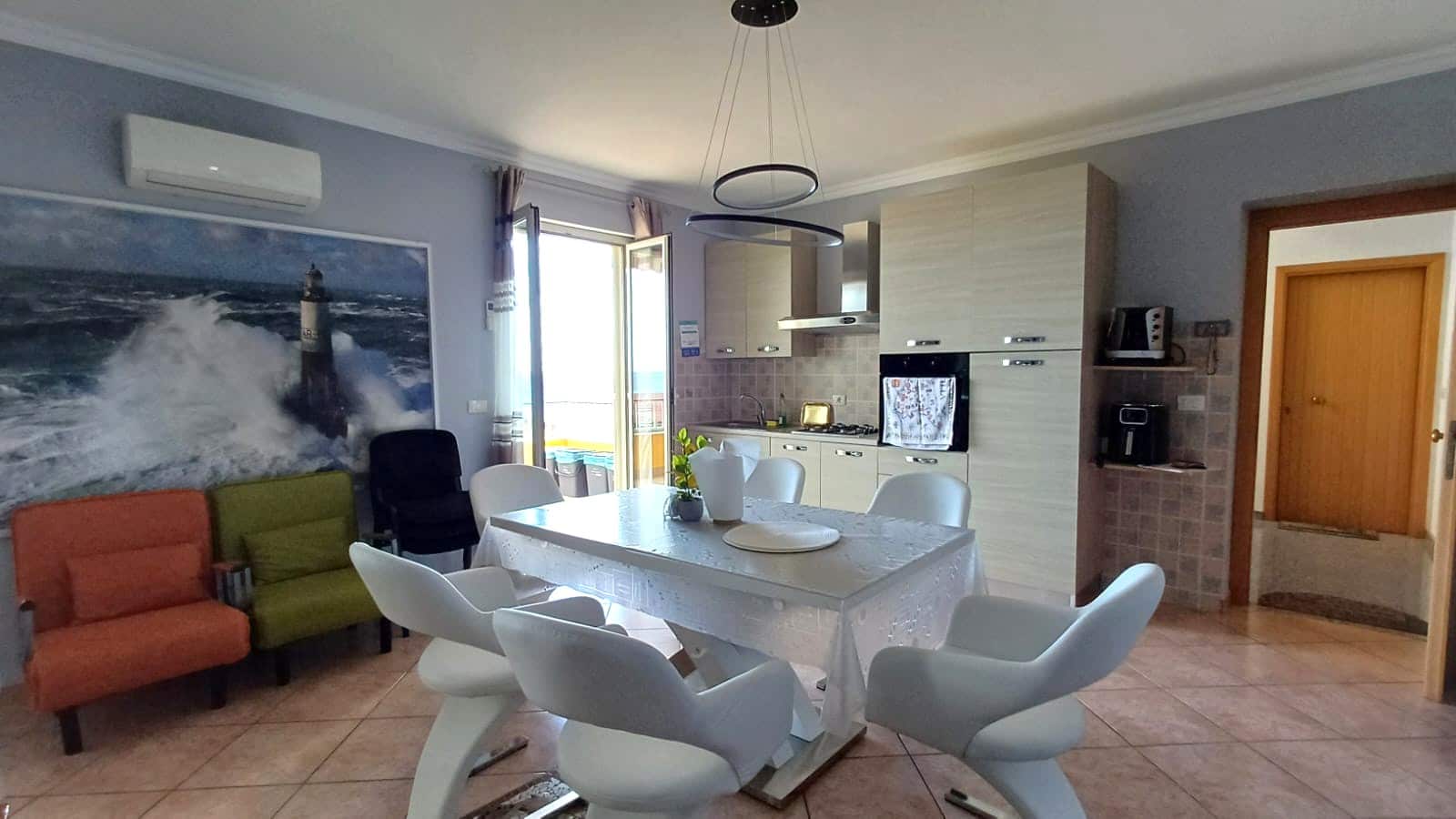 Finestra con vista sul balcone, cucina moderna e soggiorno elegante in appartamento NextCasa. Design accogliente con mobili di qualità e dettagli curati per un'esperienza abitativa di comfort e stile.