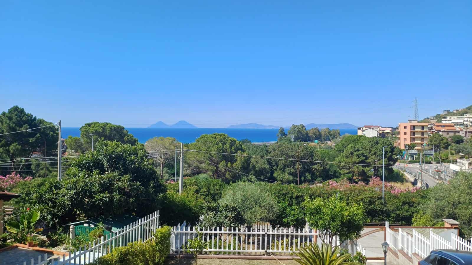 Verde panorama vista mare con case e natura, vista mare cristallina e isole all'orizzonte, scenario tranquillo e suggestivo, perfetto per case sul lungomare o residenze con vista panoramica.