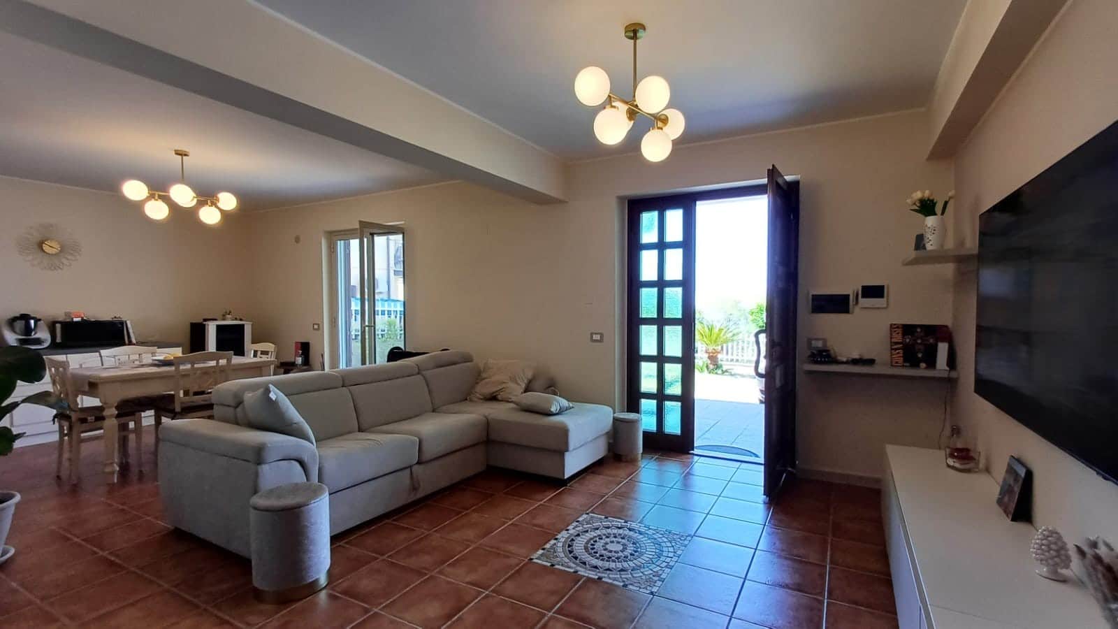 Luminoso soggiorno con divano beige e accesso a terrazza, arredato con elementi moderni e di design, ideale per vivere con comfort e stile.