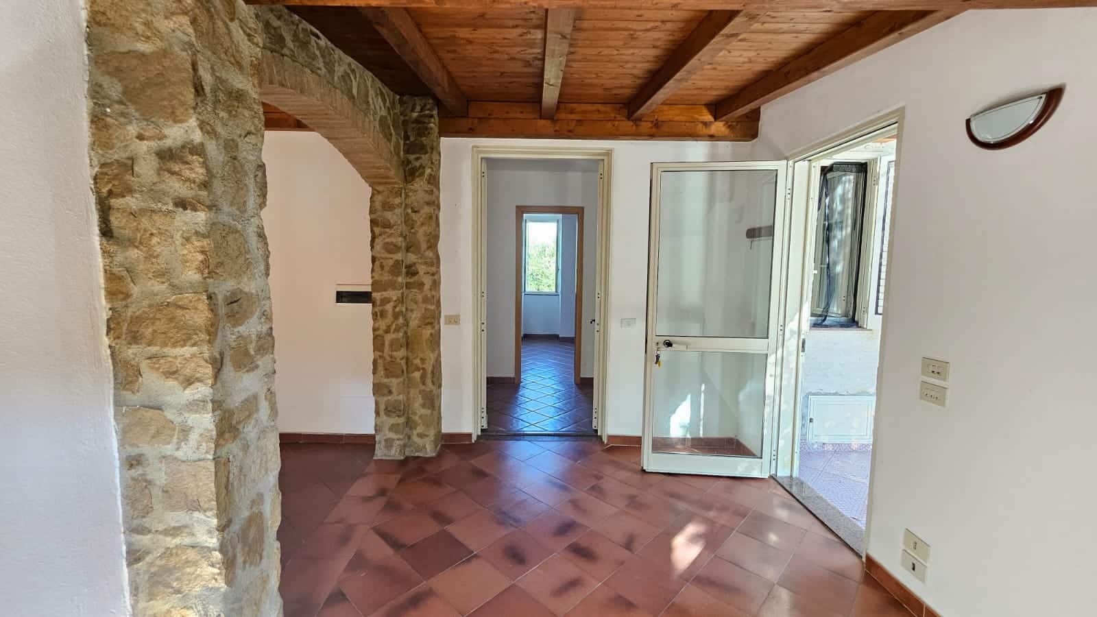 Fantasia di interni con pareti in pietra e soffitto in legno, spazio luminoso e accogliente in una casa in stile rustico moderno, ideale per annunci immobiliari NextCasa.