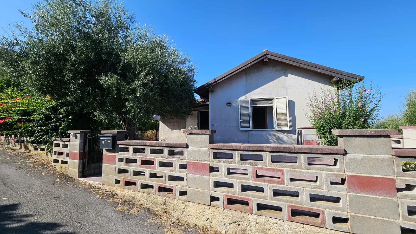 Casa indipendente con giardino e muro di recinzione in mattoni, zona tranquilla, atmosfera familiare, ideale per acquisto o investimento immobiliare.