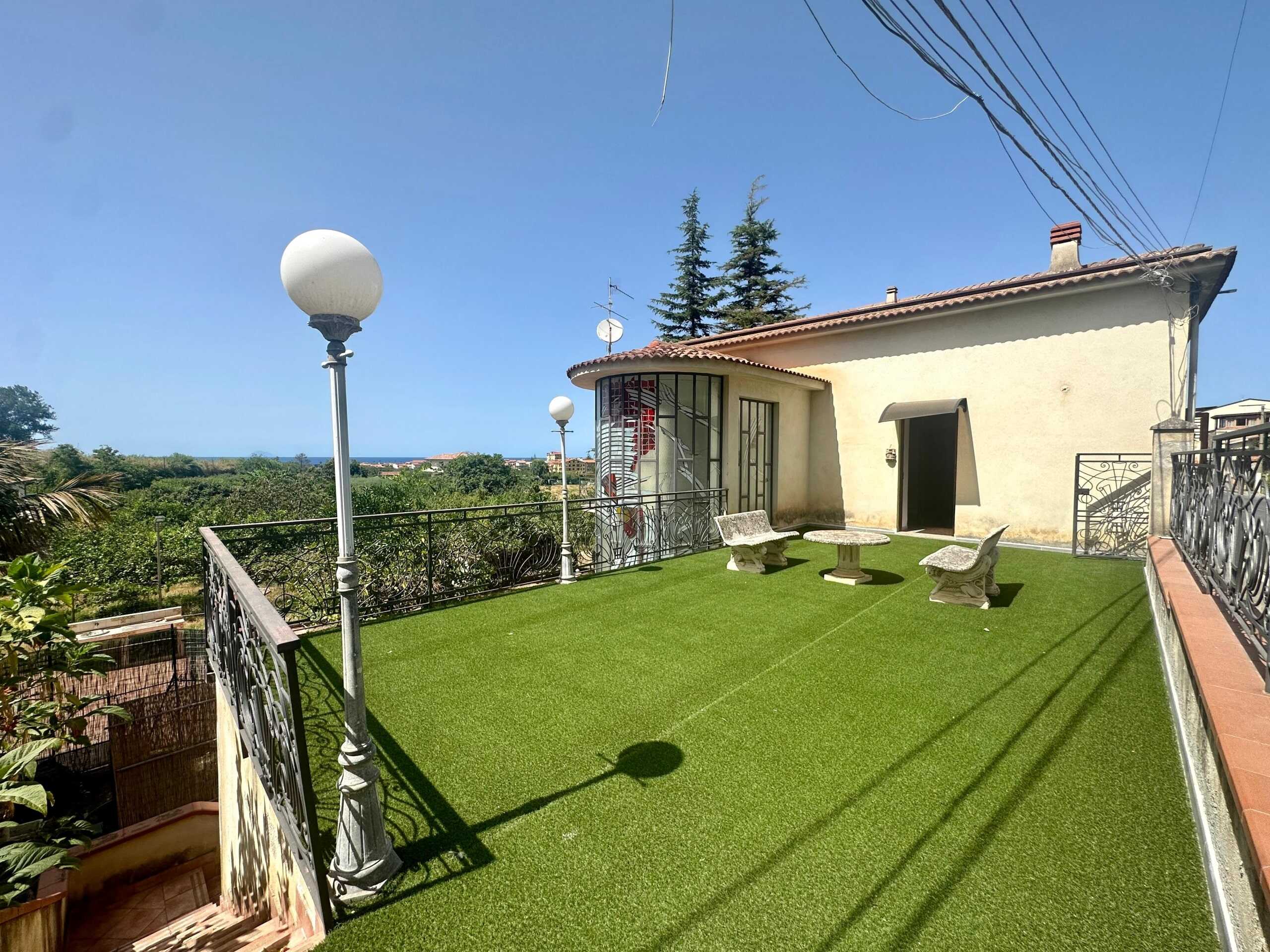 Vasto terrazzo con vista panoramica, panchine e tavolino, pavimentato con prato sintetico, vicino a ville in stile italiano, ideale per relax e momenti all'aperto, in zona tranquilla e ben servita.