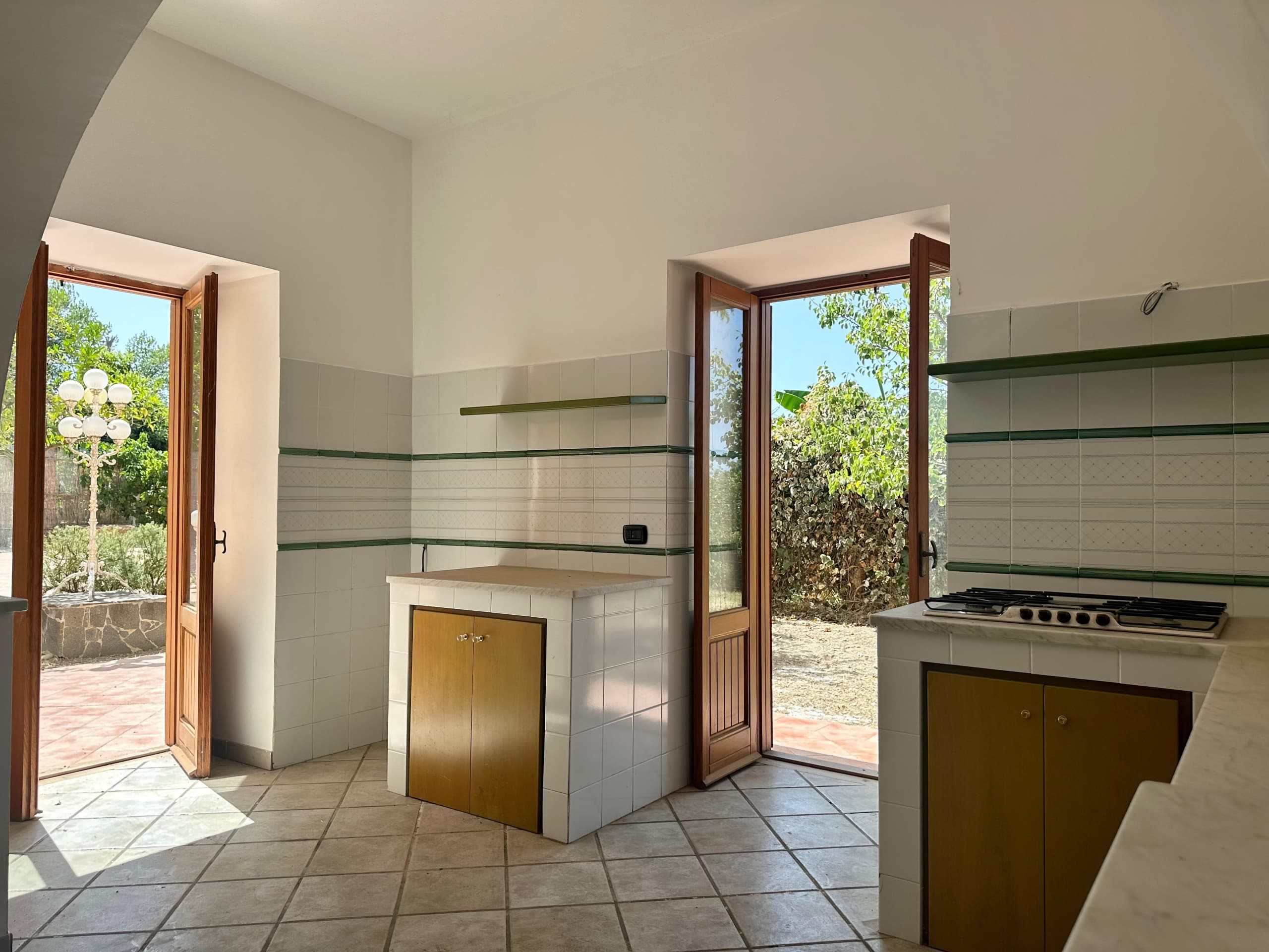 Nascosta cucina con finestre e porte di legno, spazio luminoso e arioso, vista sul giardino, piastrelle in ceramica, ambiente ideale per una casa o una proprietà in vendita a NextCasa.