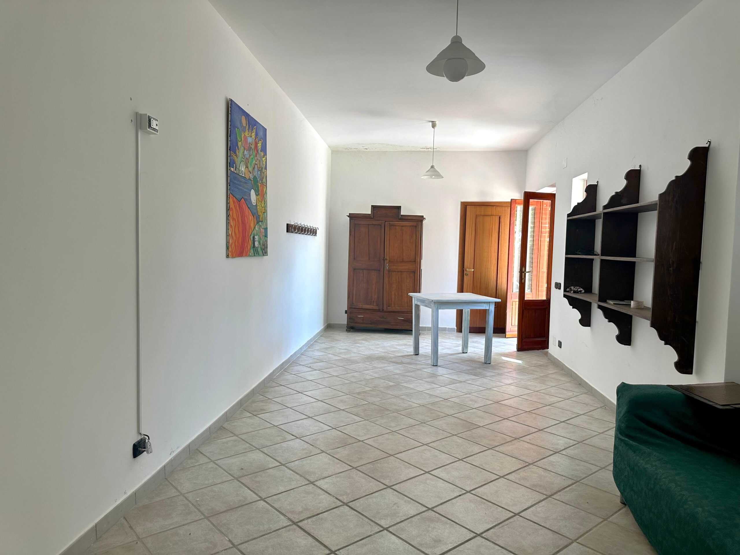 Appartamento con soggiorno ampio, arredi semplici e pareti bianche, parquet in legno, con armadio e libreria in legno scuro, luce naturale, ideale per investimento o prima casa.