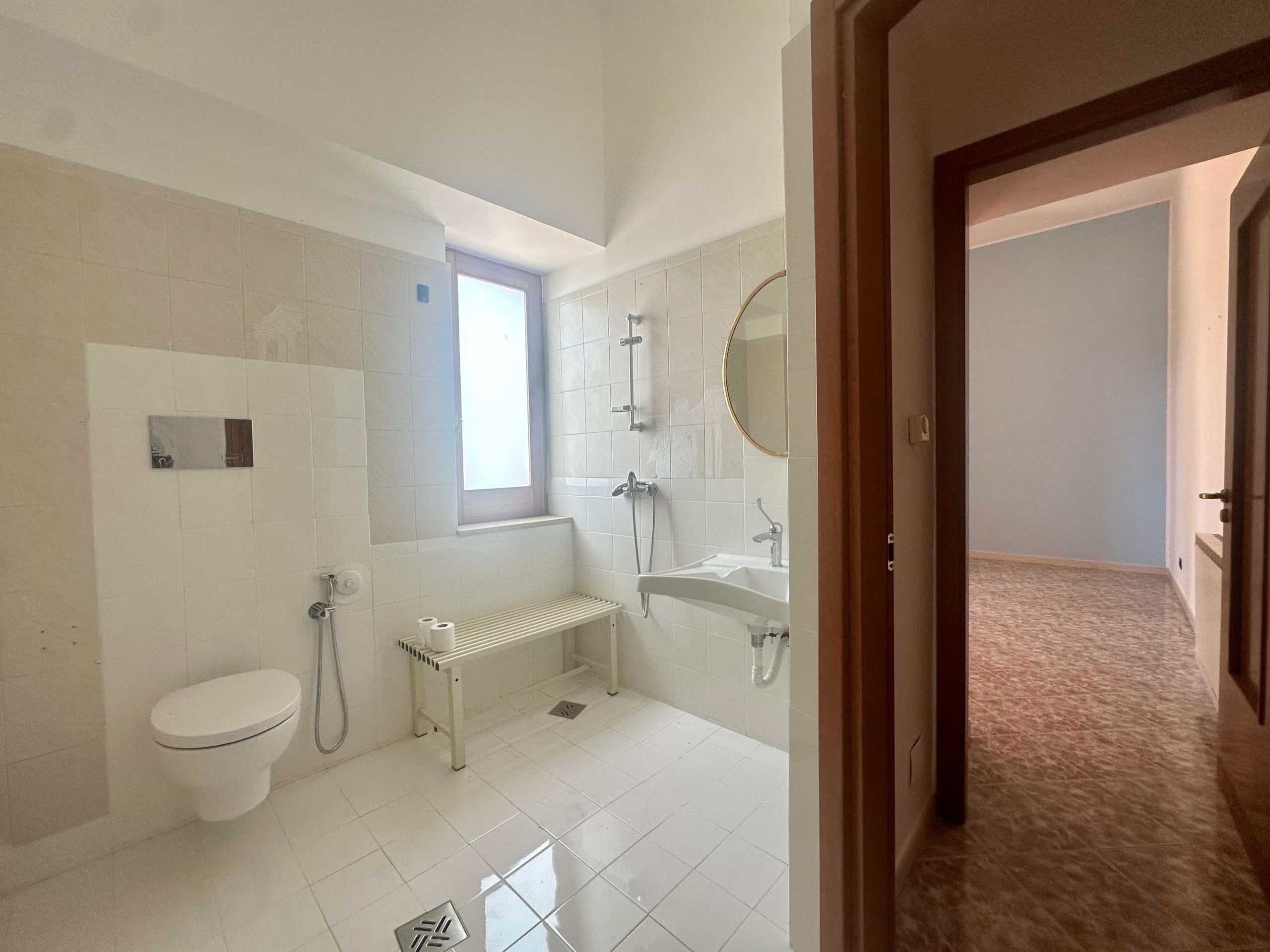 Lavabo, doccia e servizi igienici in bagno modernamente arredato con luce naturale. Ideale per residenze confortevoli, con finiture pulite e pavimenti antiscivolo. Perfetto esempio di bagno funzionale e accattivante.