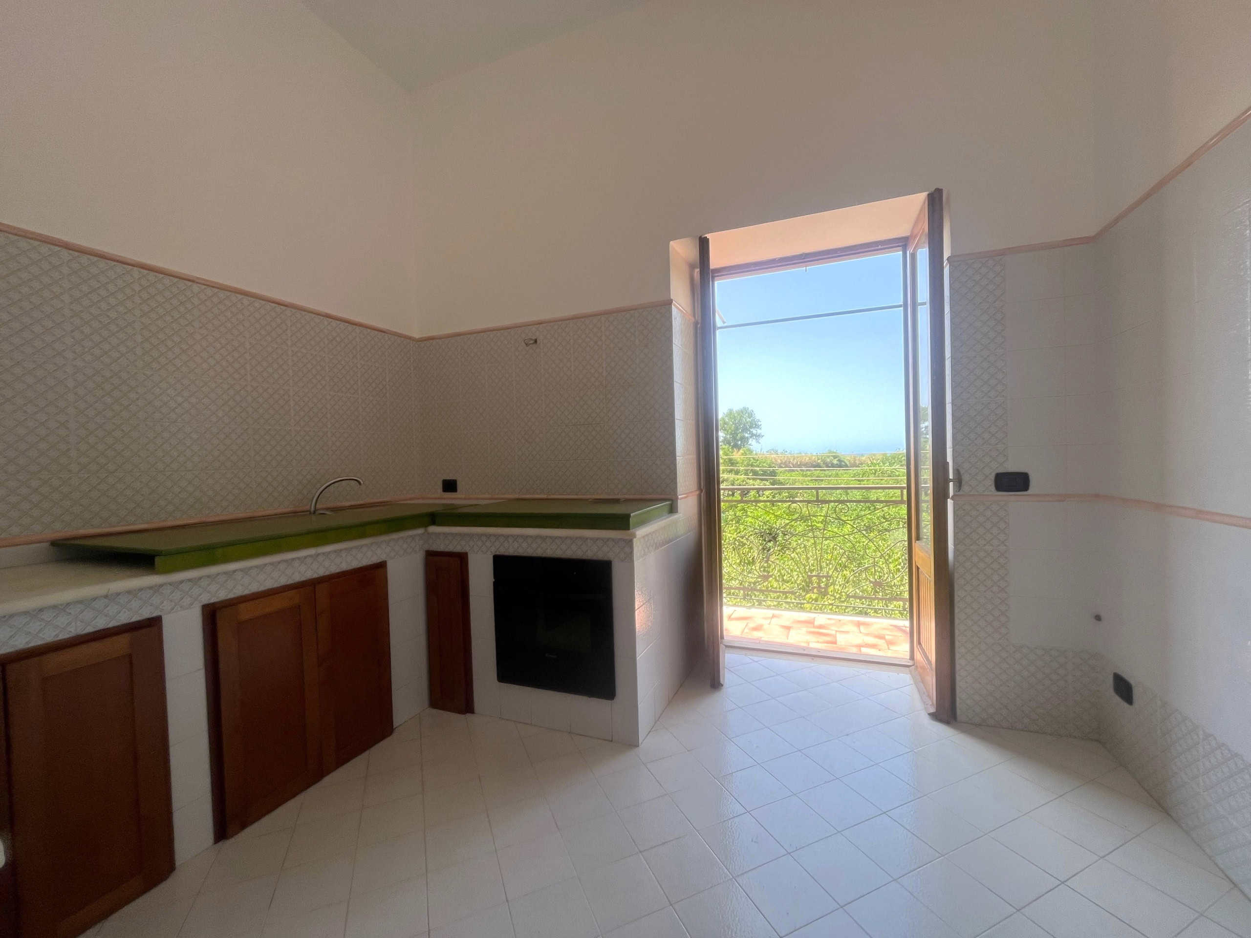 Finestra aperta su un balcone con vista panoramica sulla natura e il paesaggio circostante, luce naturale in cucina, ambiente luminoso e spazioso, ideato per chi cerca immobili con vista e ambienti soleggiati.