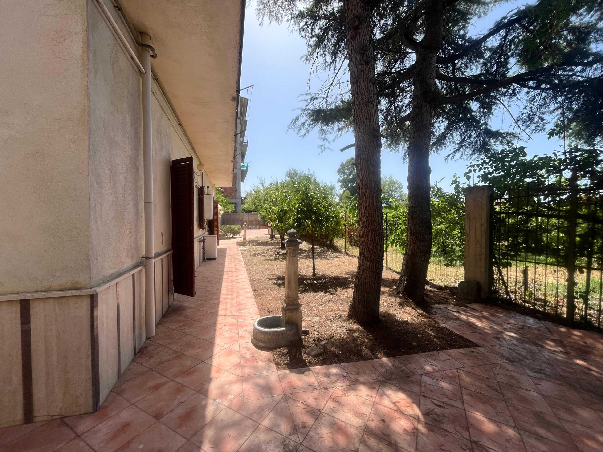 Serbatoio acqua esterno, giardino privato con alberi, terrazza in piastrelle, casa rustica con porte in legno, ambiente tranquillo per immobili in Toscana.