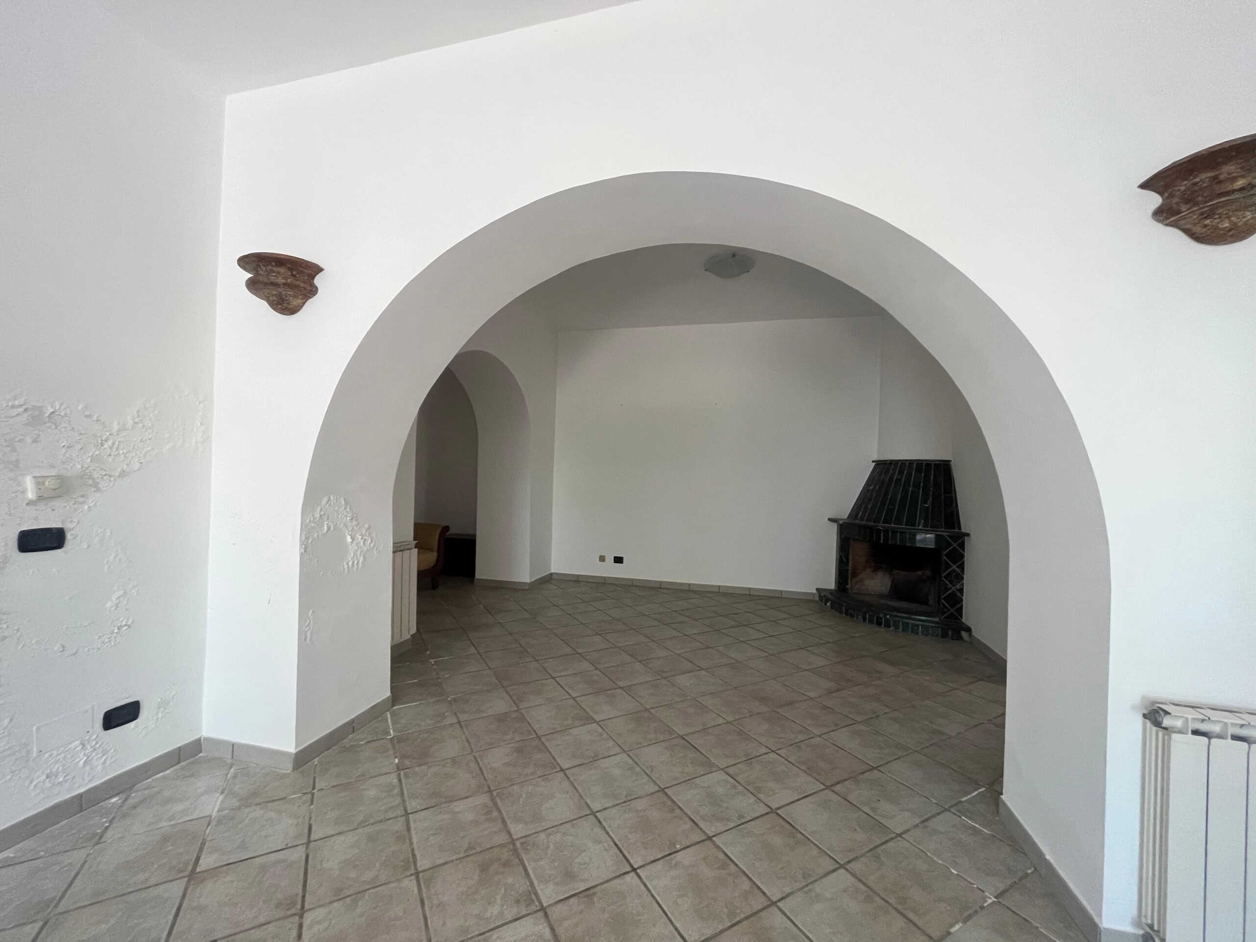 Architettura interna, grande soggiorno con camino in stile rustico, pareti bianche, pavimento in piastrelle, angoli accoglienti in una casa di campagna o villa.