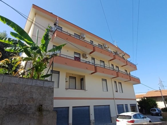 Grattacielo residenziale con balconi ad angolo, appartamenti moderni con aria condizionata, vista su strada con automobili, zona urbana tranquilla, vicino a servizi pubblici e aree verdi, edifici in stile contemporaneo.