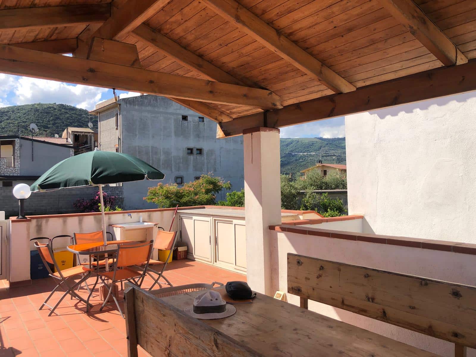 Balcone con vista sulle colline, arredato con tavolo, sedie e ombrellone, perfetto per vivere momenti all'aperto e godere della natura.