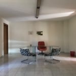Soggiorno elegante con tavolo in vetro, sedie zebrate e zona studio con sedia rossa, arredamento minimalista, pavimento in piastrelle chiare, pareti bianche e pattern di quadri astratti.