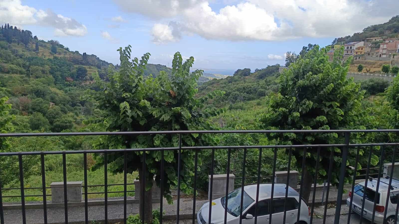 Bellissimo panorama naturale con colline verdi, alberi e cielo sereno, visibile dal balcone di una proprietà NextCasa in vendita o affitto, con vista sulla natura e sui villaggi circostanti.