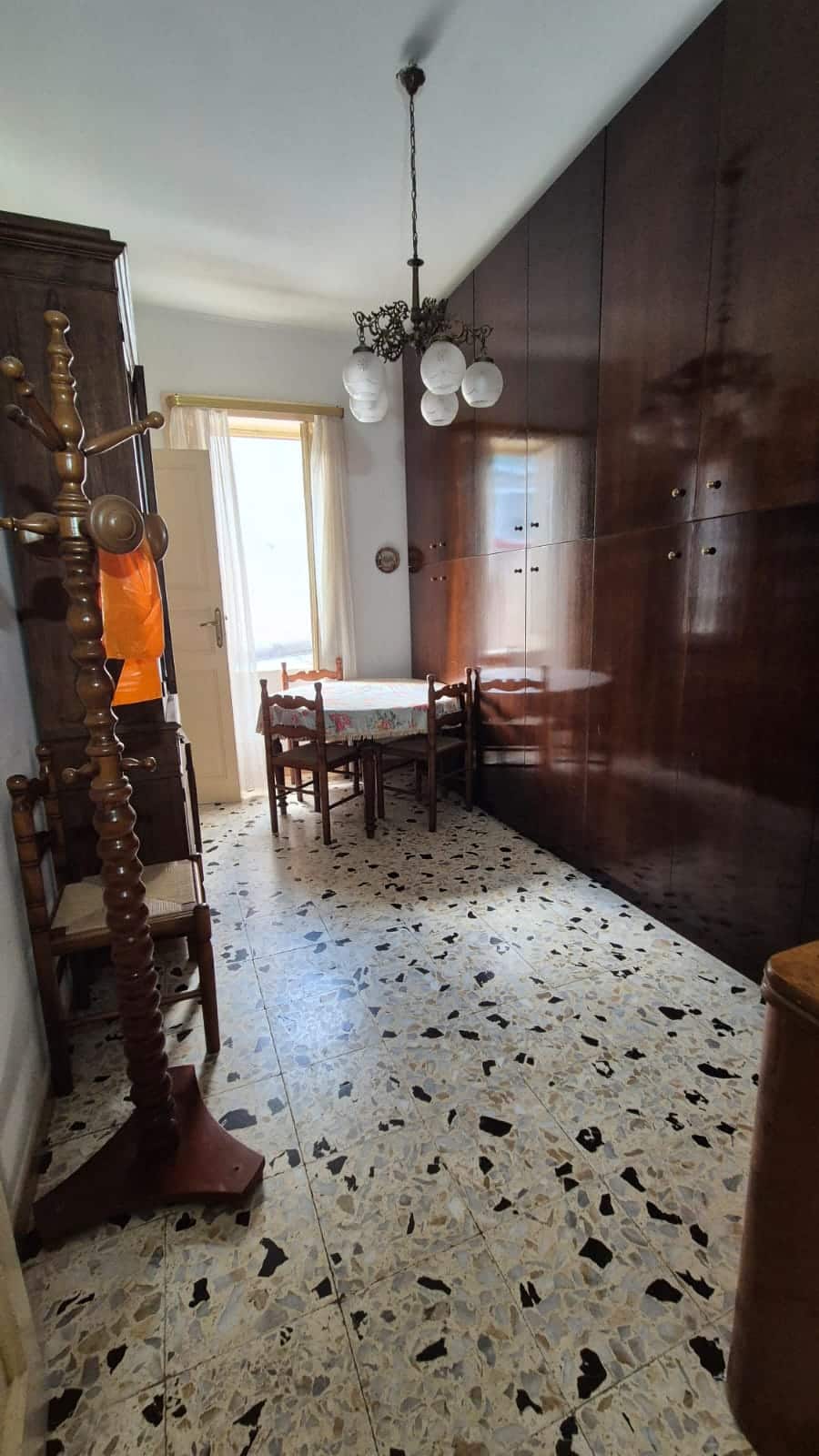 Porta di ingresso con luce naturale, arredamento vintage e pavimento in marmette, con armadi in legno e lampadario a soffitto, ideale per ambienti abitativi di charme.