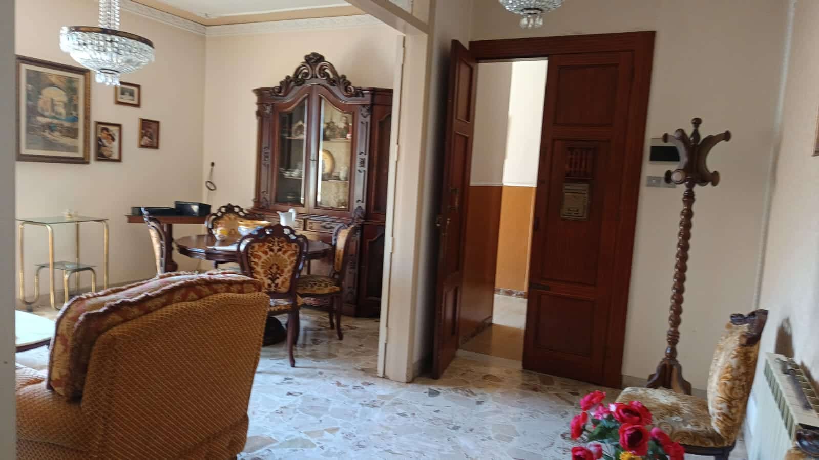 Elegante soggiorno con mobili in stile classico, pareti decorate, lampadario di cristallo, e dettagli d'epoca, ideale per case di pregio e immobili di alta qualità.