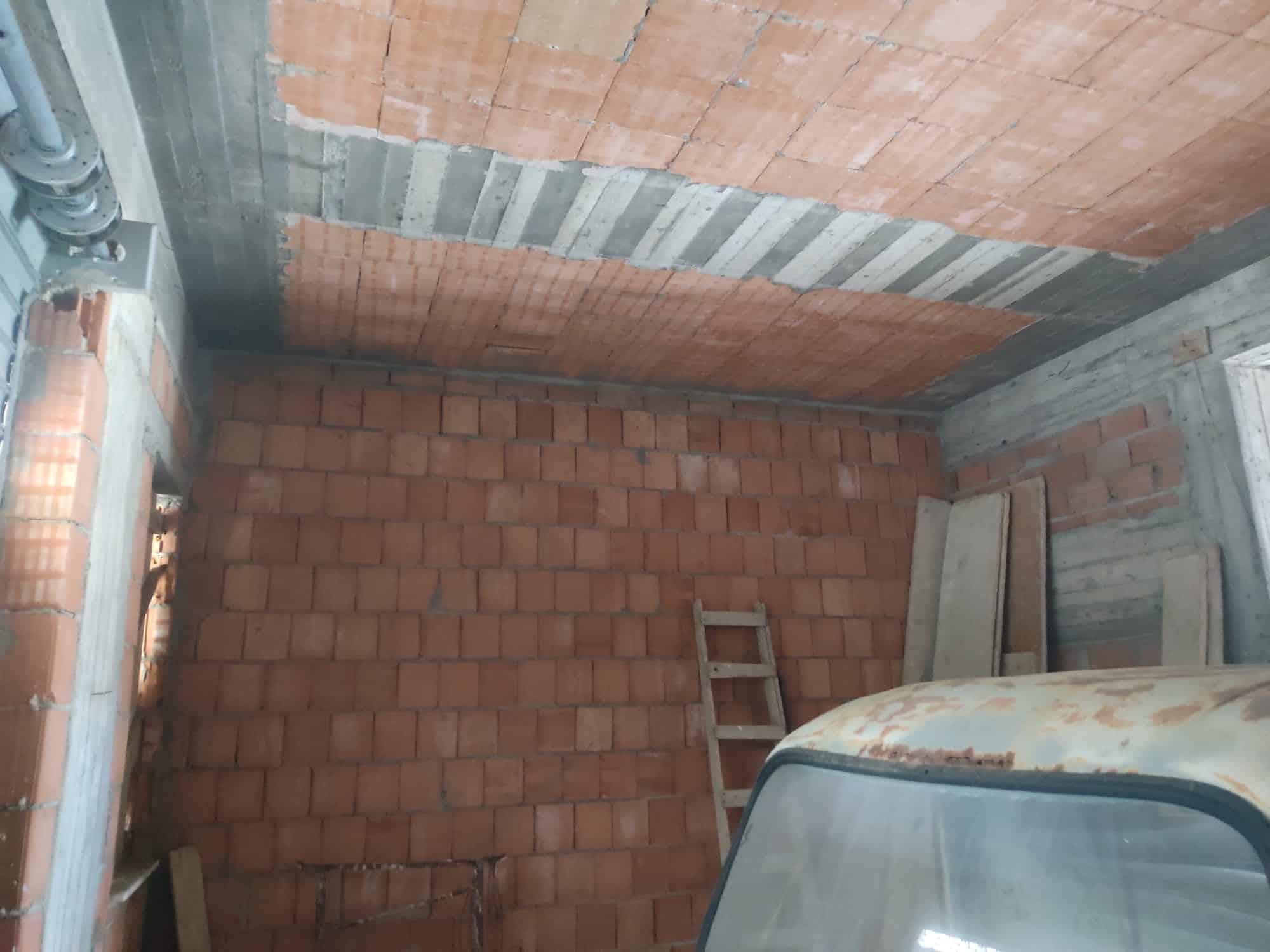 Parete interna in costruzione con mattoni rossi e dettagli in cemento, ambiente di cantiere per ristrutturazione casa.
