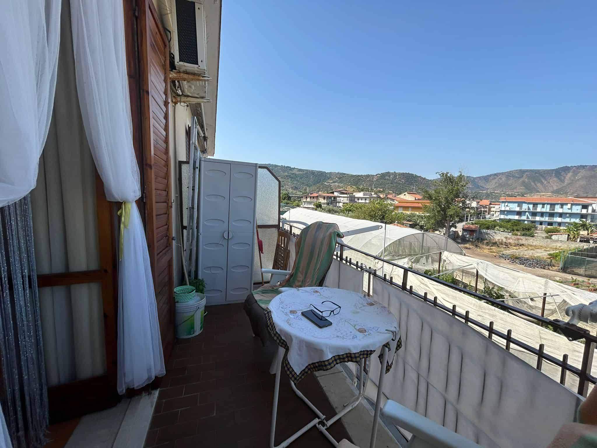 Vista panoramica sul balcone di una casa in provincia di Arezzo, con arredi esterni, tende e vista sulle colline toscane, ideale per relax e colazioni all'aperto.