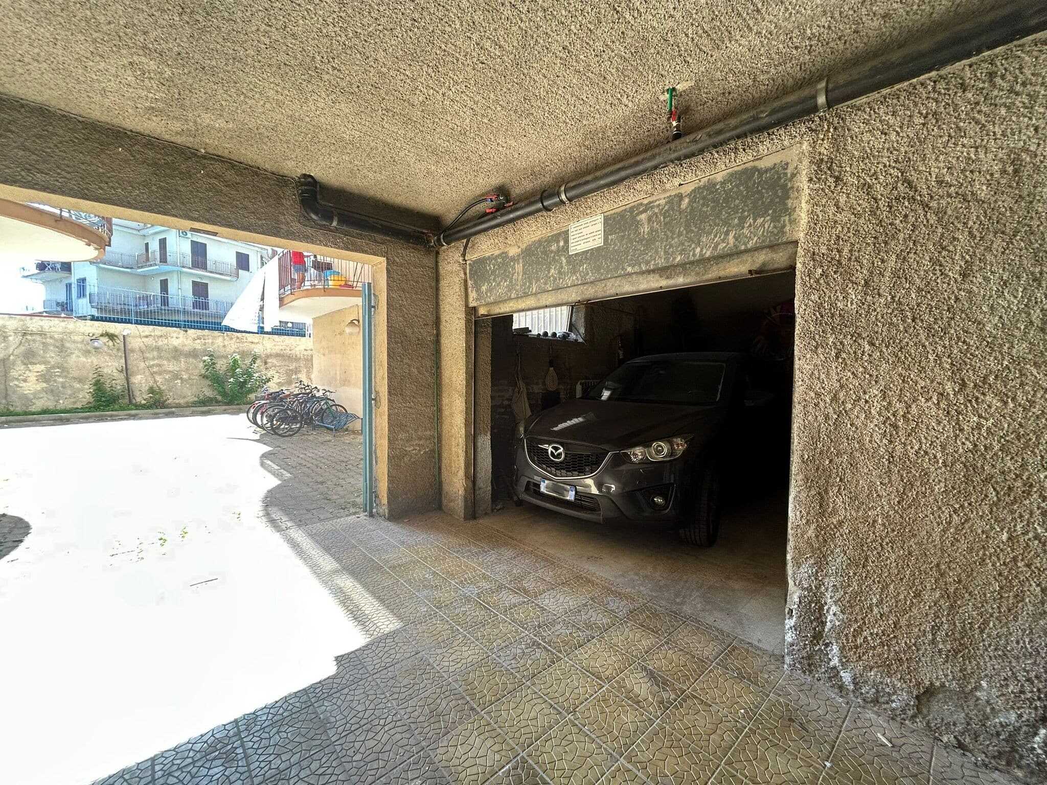 Auto nel garage condominiale, vista dall'ingresso esterno con spazio per biciclette e accesso alla strada.