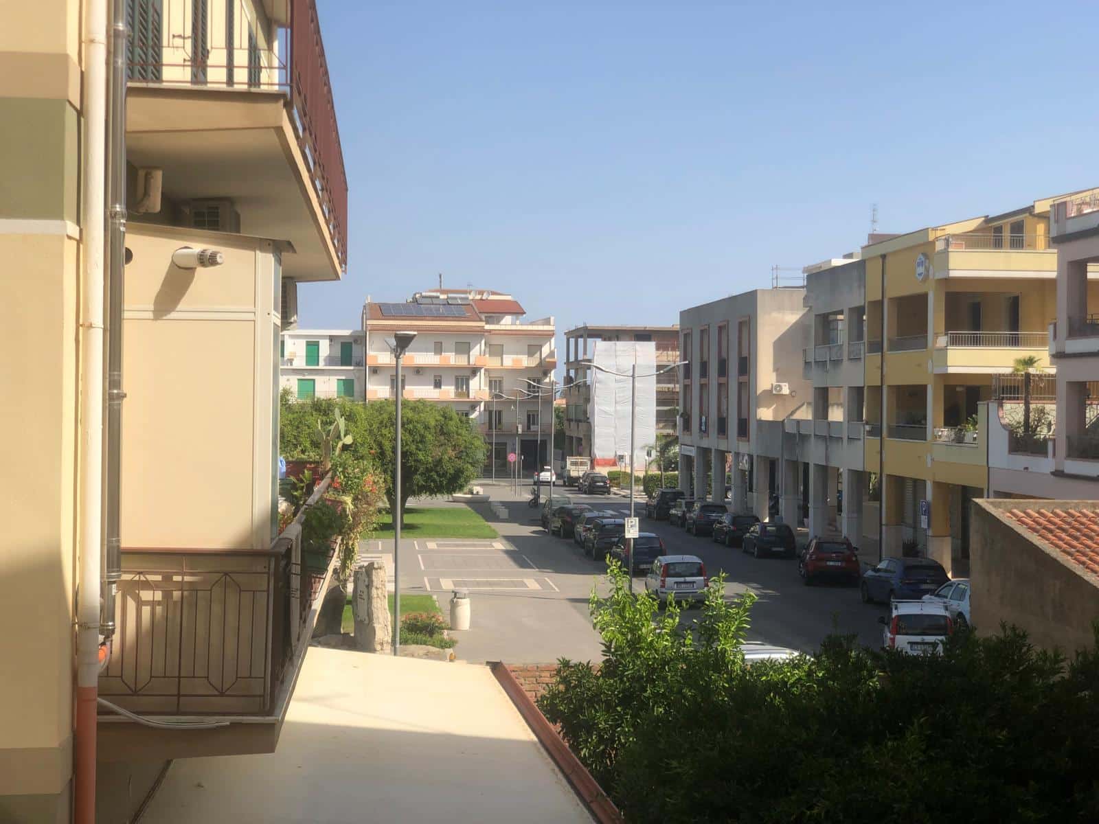 VISTA PANORAMICA di un quartiere residenziale con edifici moderni, strada con parcheggio e un'area verde, ideale per immobili e case in vendita o affitto a NextCasa.